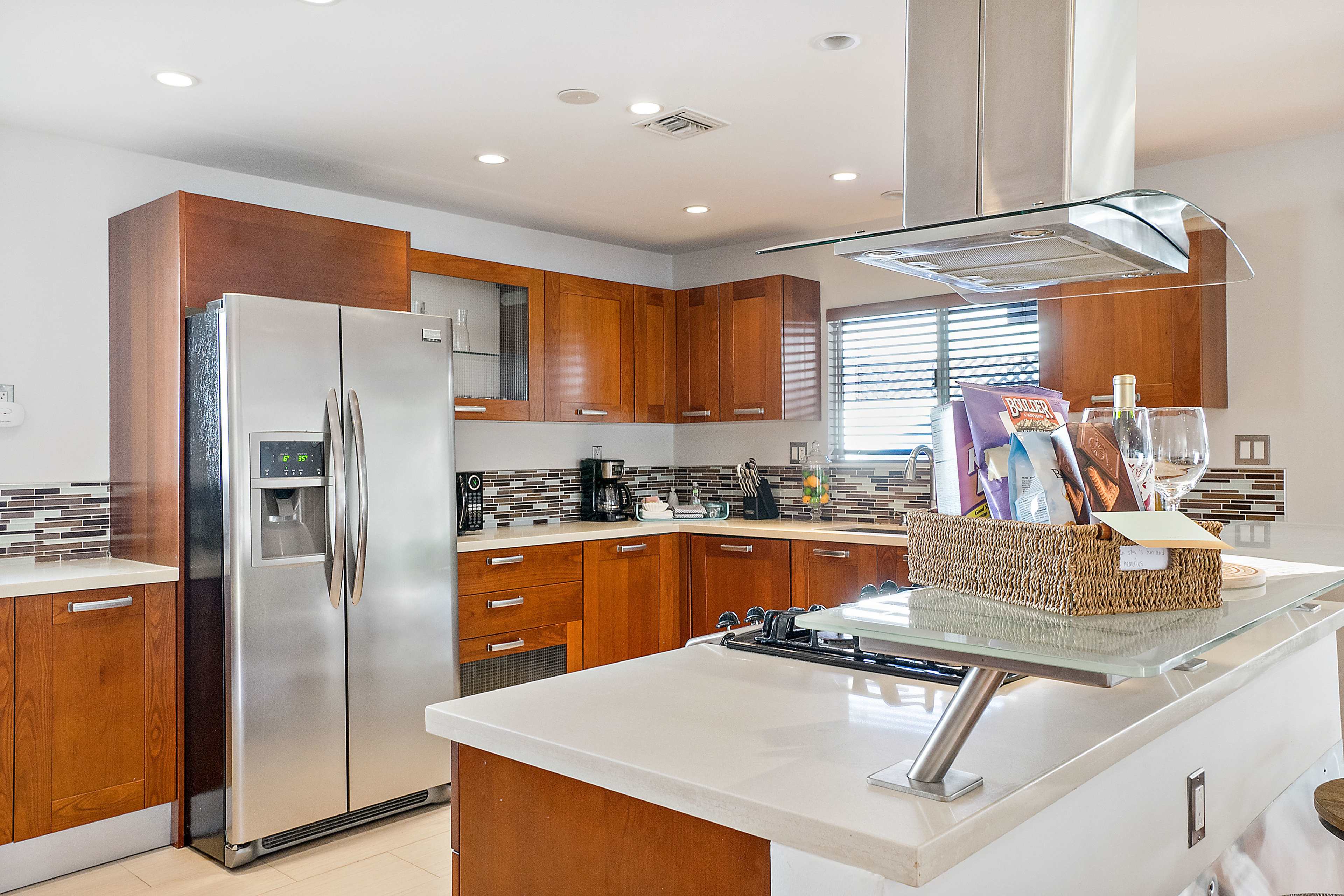 A modern kitchen featuring wooden cabinetry, stainless steel appliances, and a countertop with a basket of items.