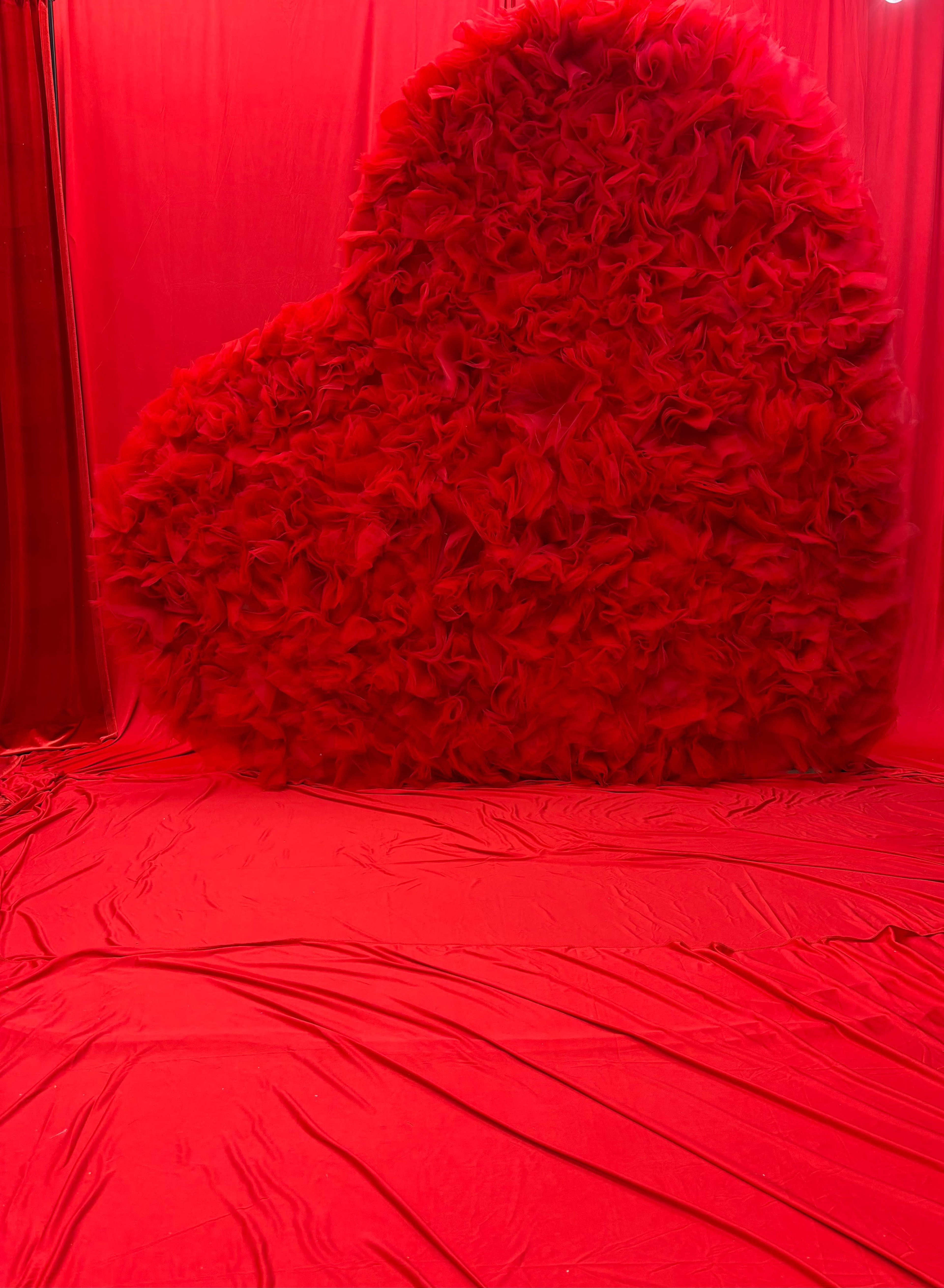 The scene features a large, heart-shaped structure made of textured material, set against a red backdrop and floor.