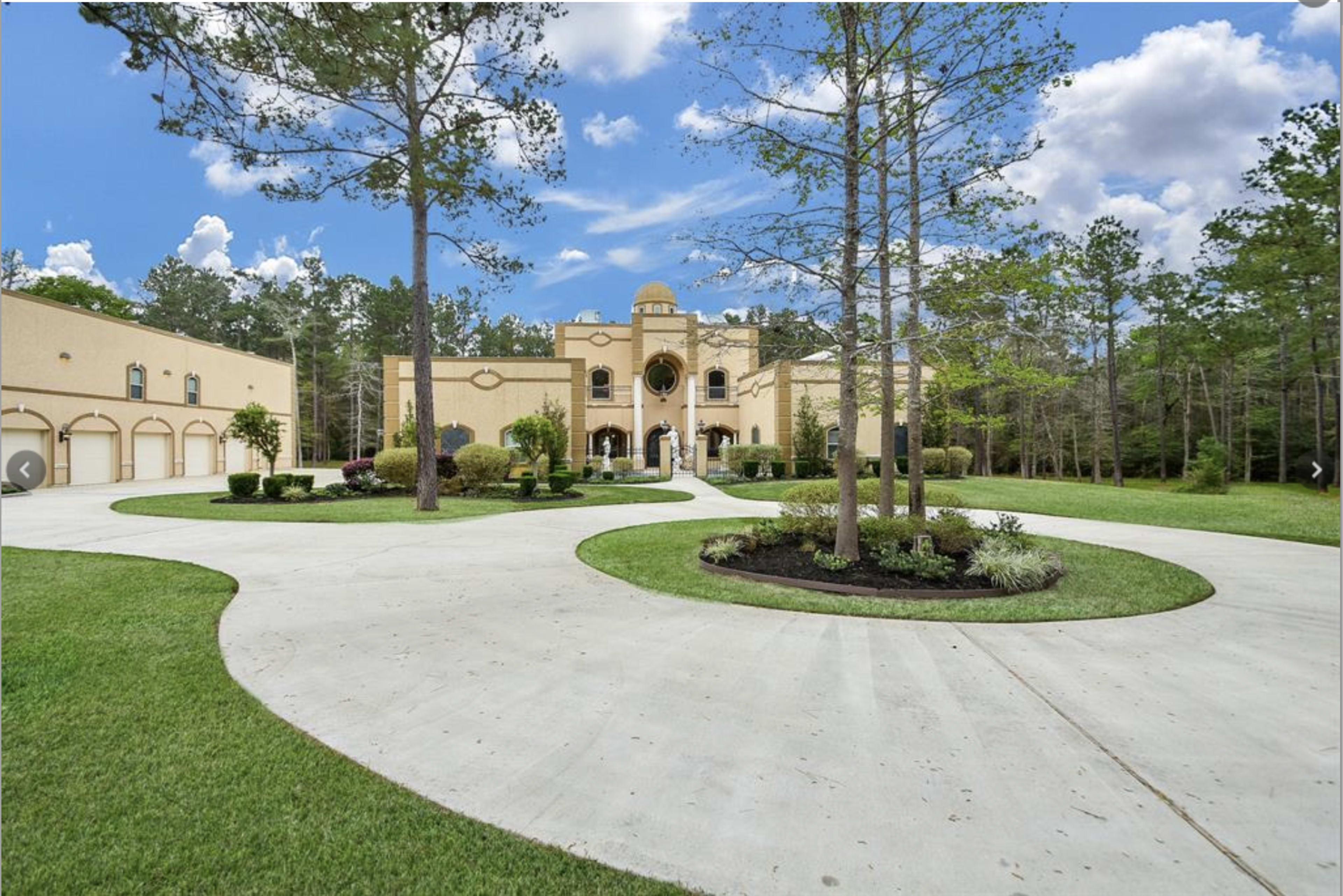 A large, two-story building with a decorative facade, surrounded by a circular driveway and landscaped greenery.