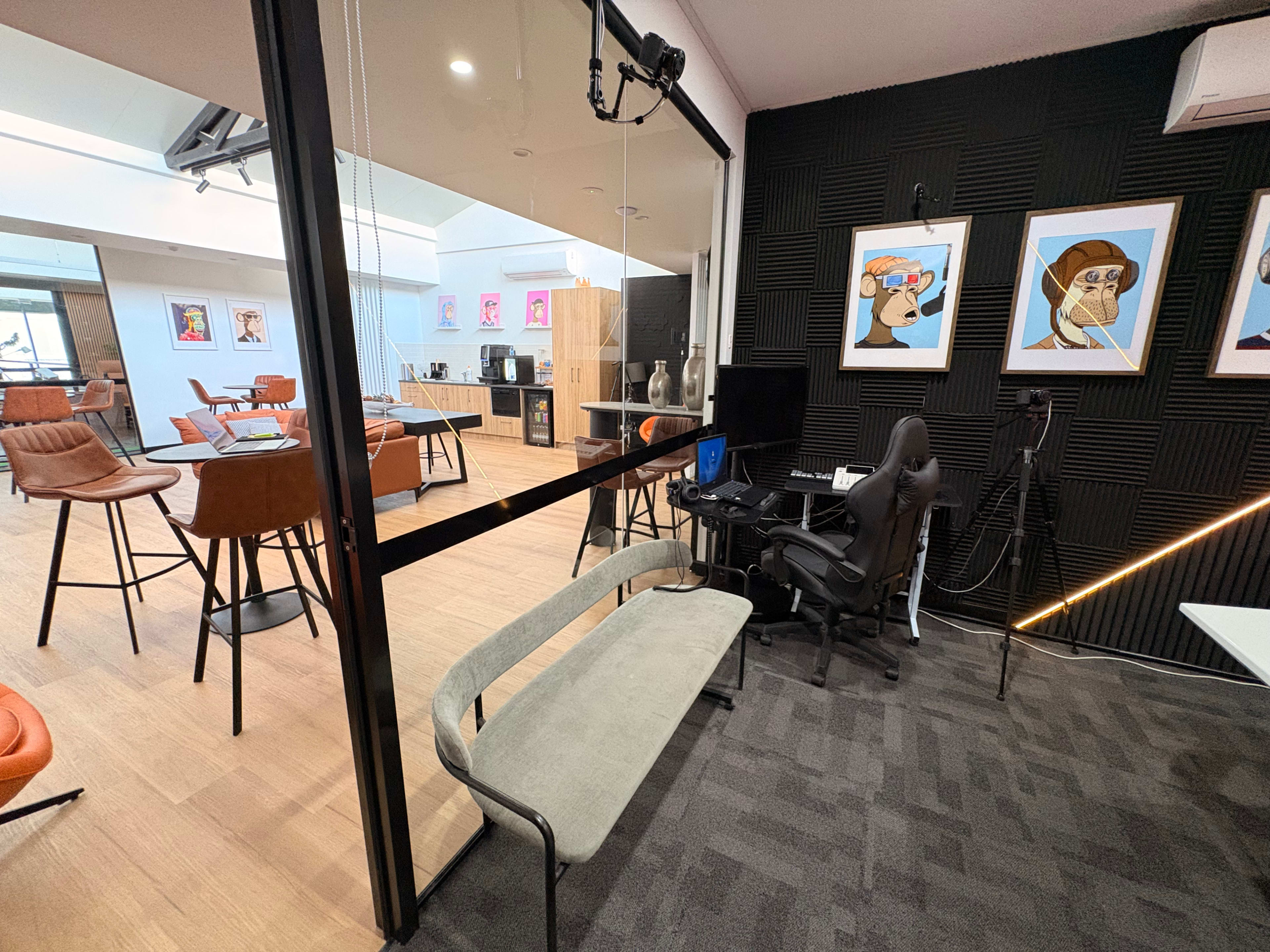The image shows a modern office space featuring a swing seat, a desk with a gaming chair, and various artwork on the walls.