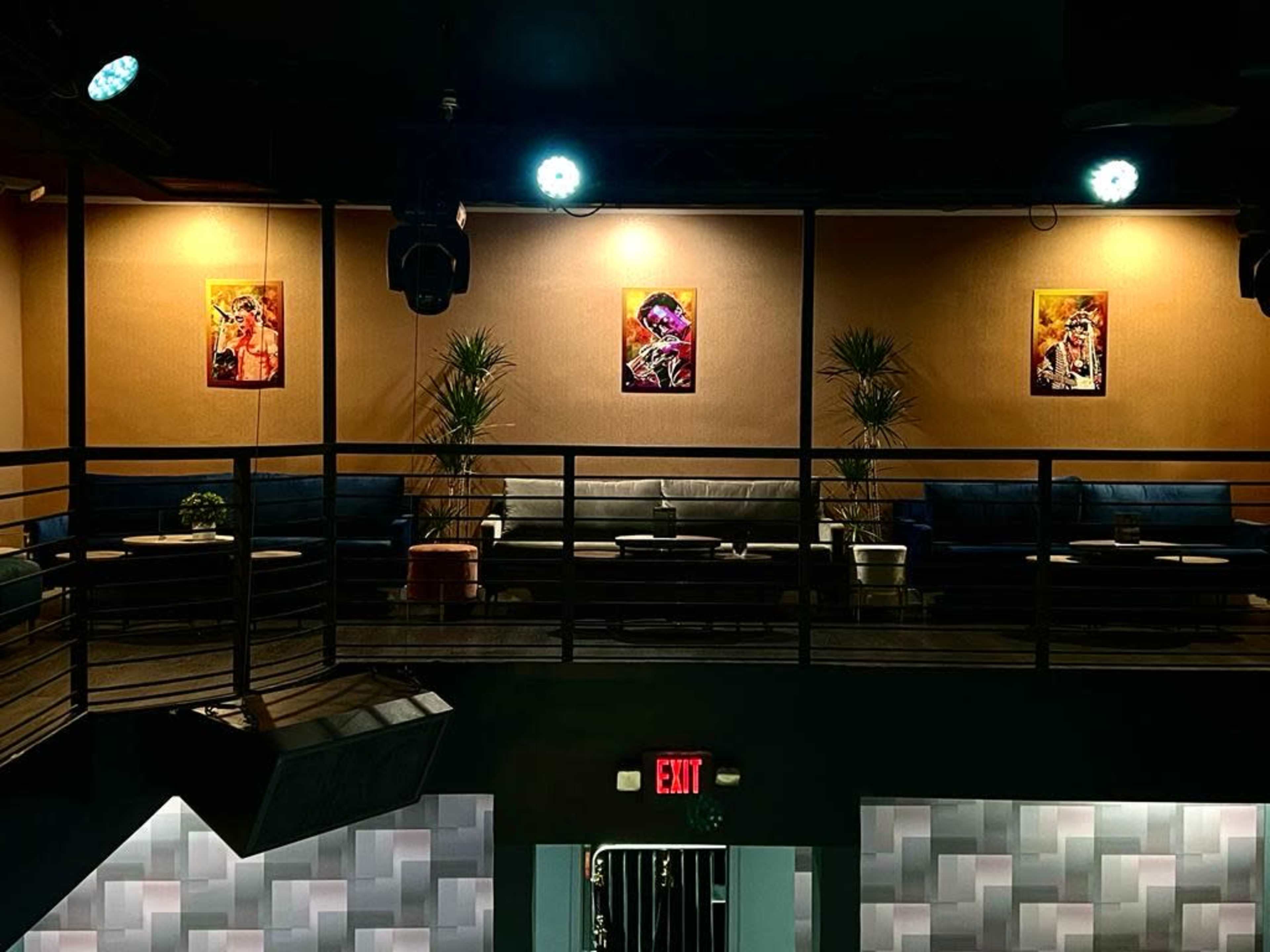 A modern lounge area with blue sofas, artwork on the walls, and indoor plants.