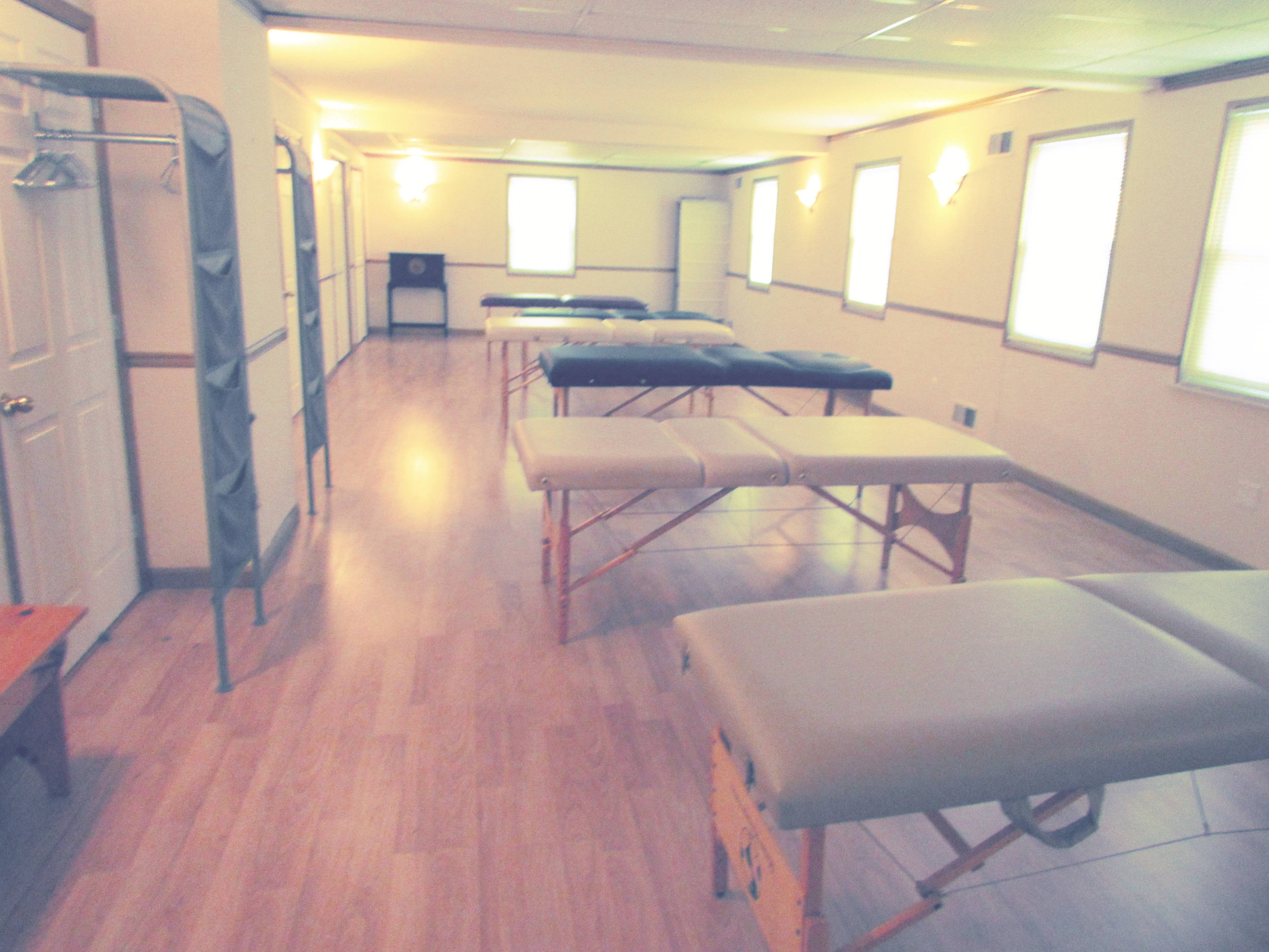 A massage therapy room with several massage tables set up in a spacious, well-lit environment.