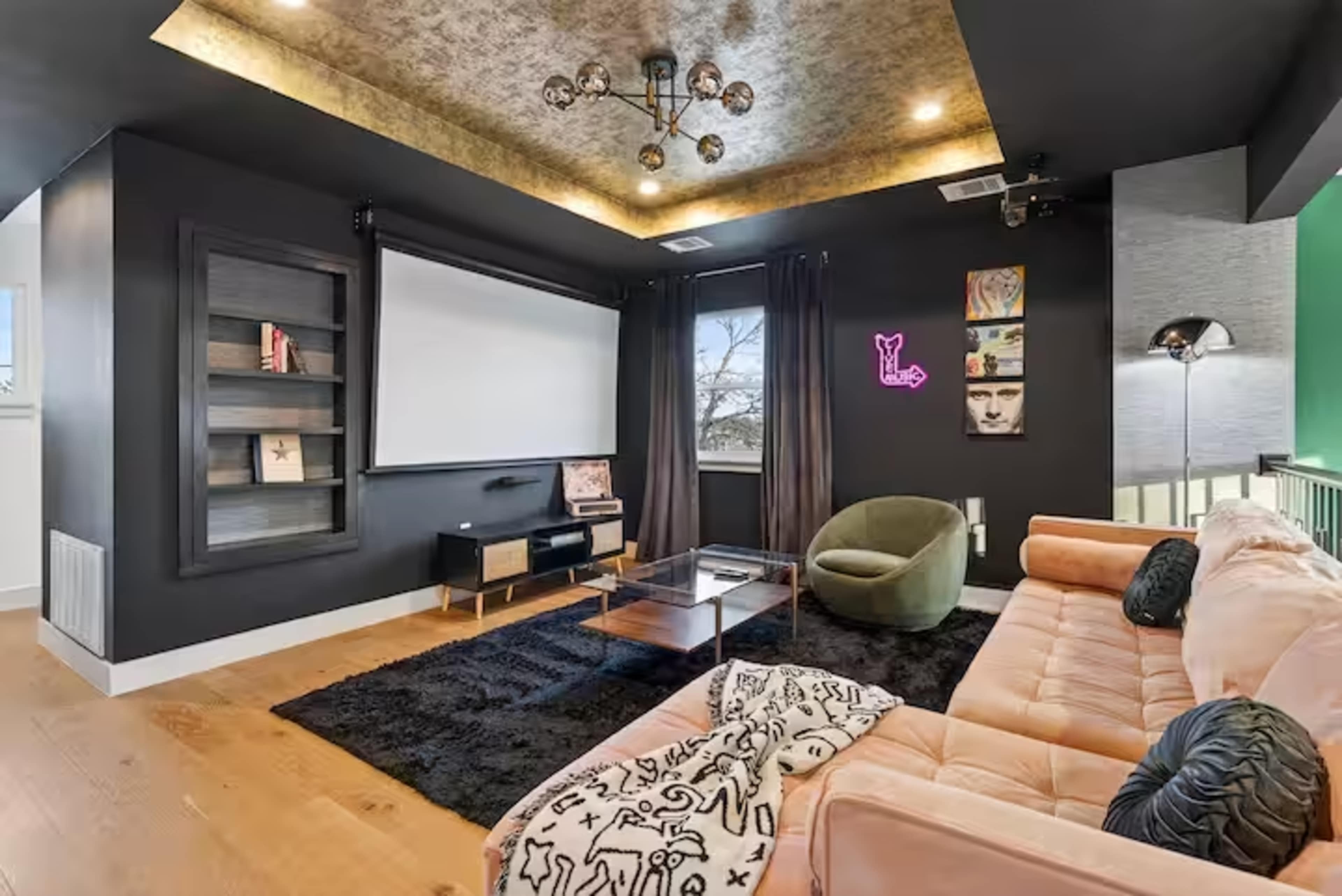 The room features a modern entertainment area with a large screen, plush seating, and a textured ceiling.