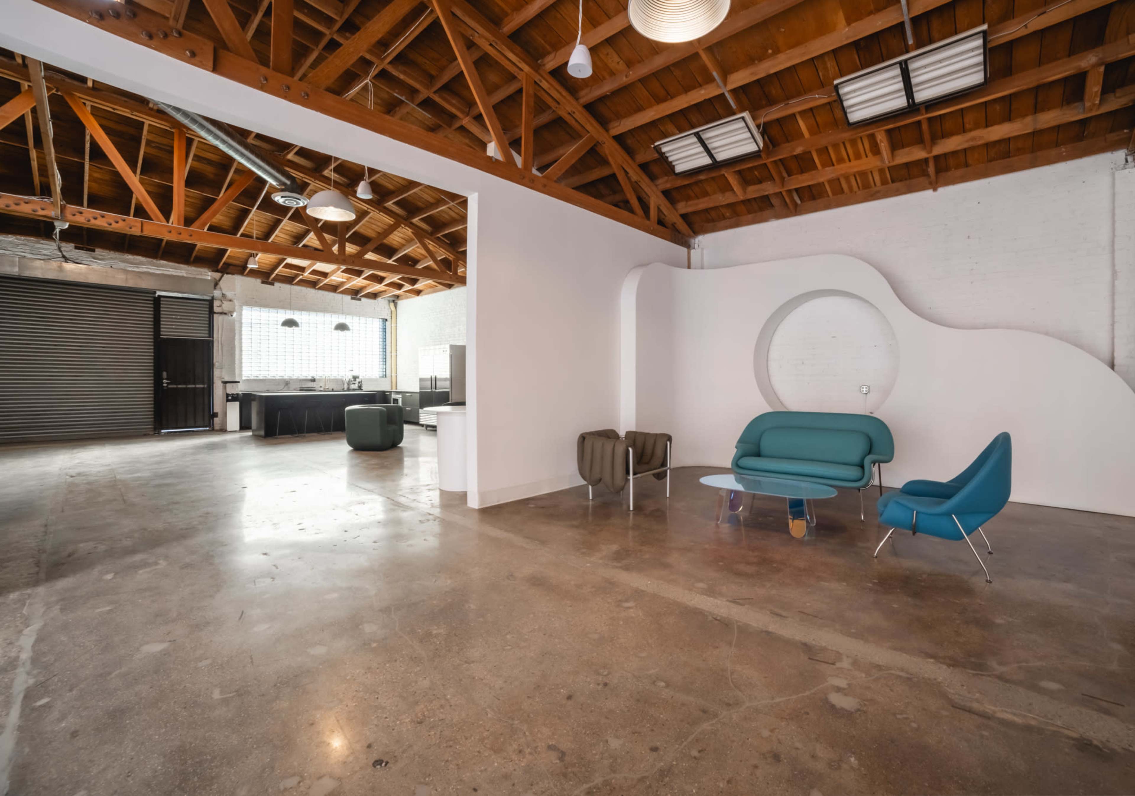 A spacious, open interior with a polished concrete floor, wooden beams, and contemporary seating arrangements against a minimalist backdrop.