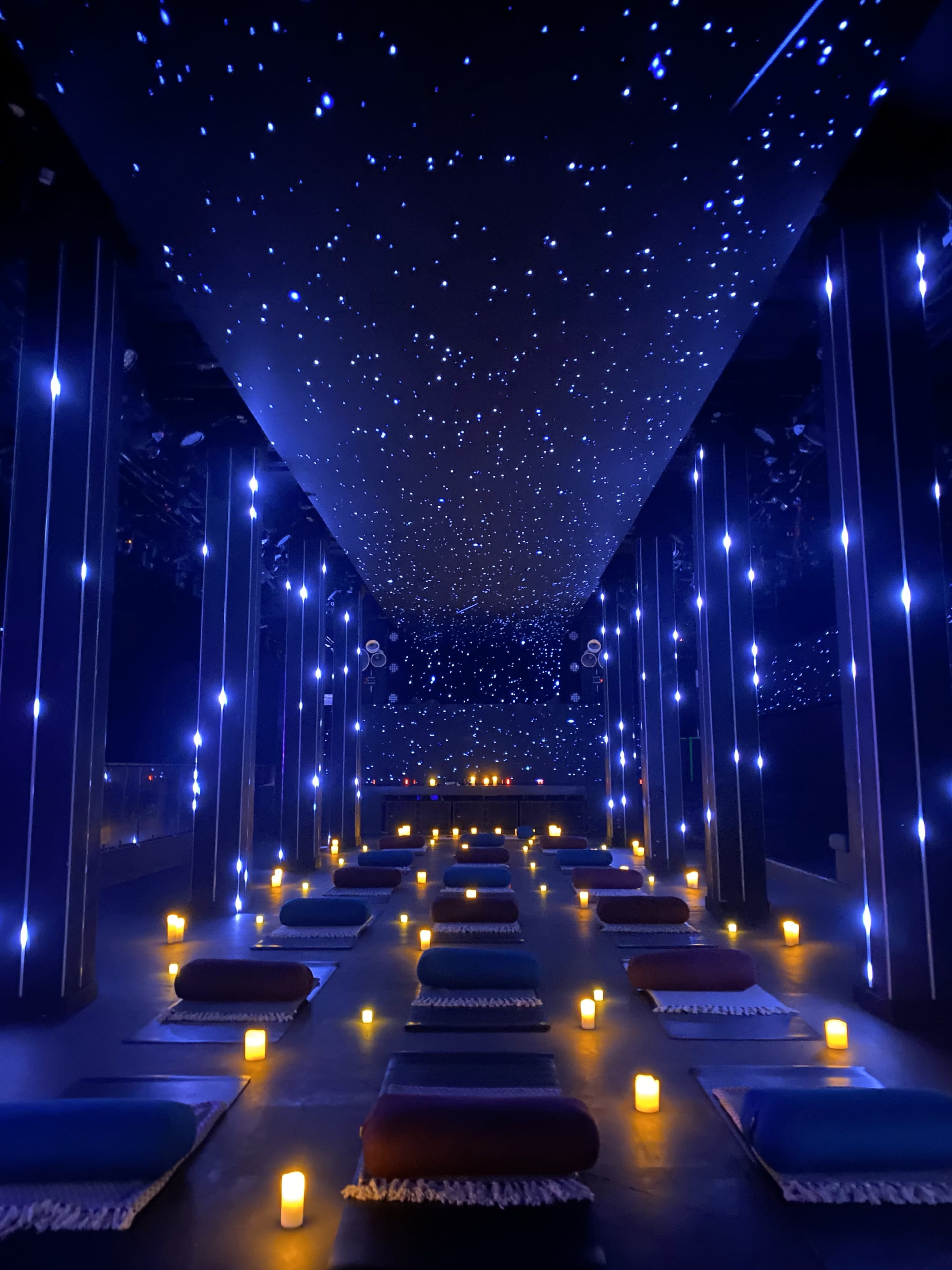 A dimly lit meditation space with cushions arranged on the floor and a starry ceiling illuminated by soft lights.