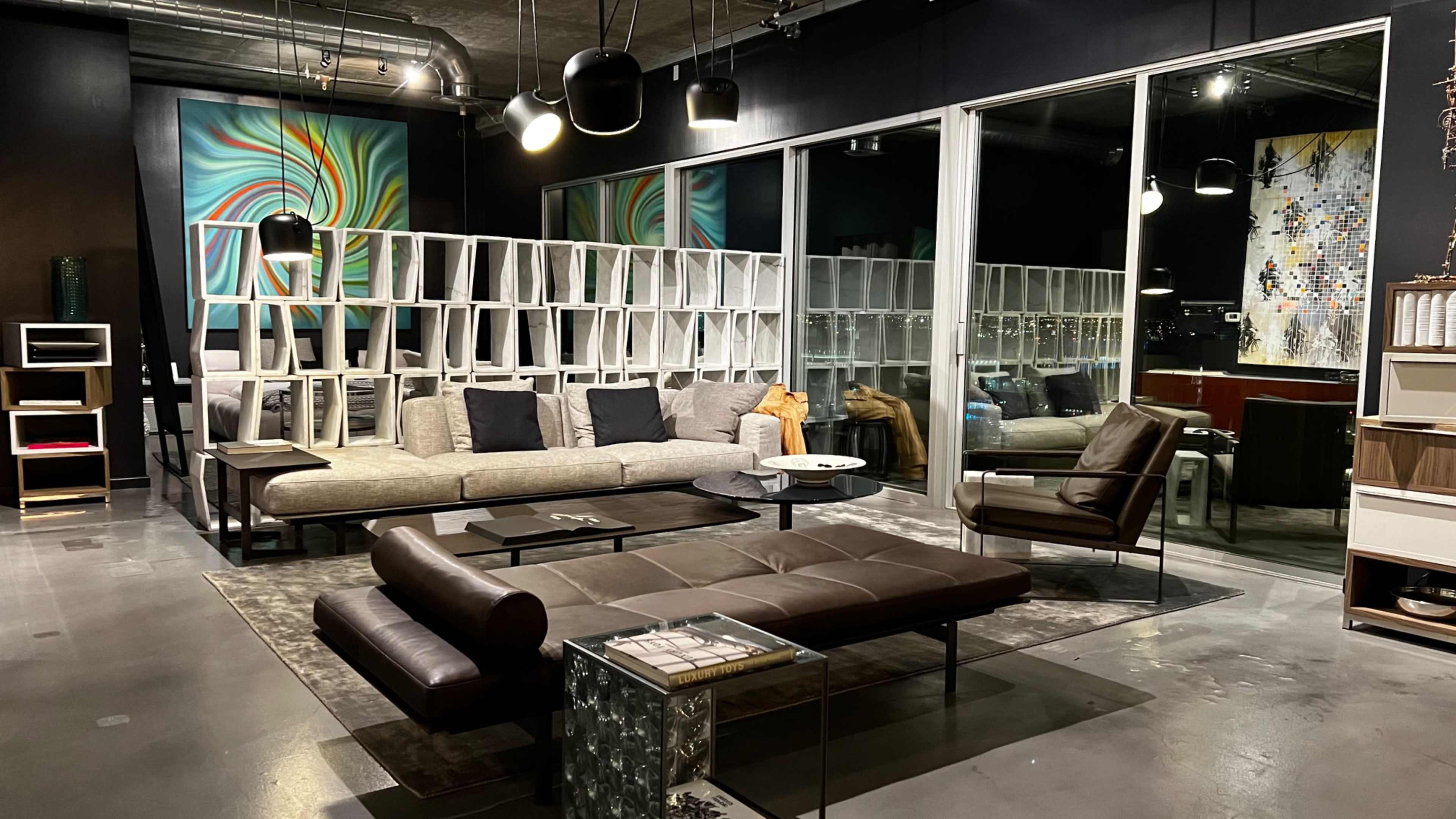 A modern living room featuring a sectional sofa, a coffee table, and large windows with city views, all arranged in a stylish, open space.