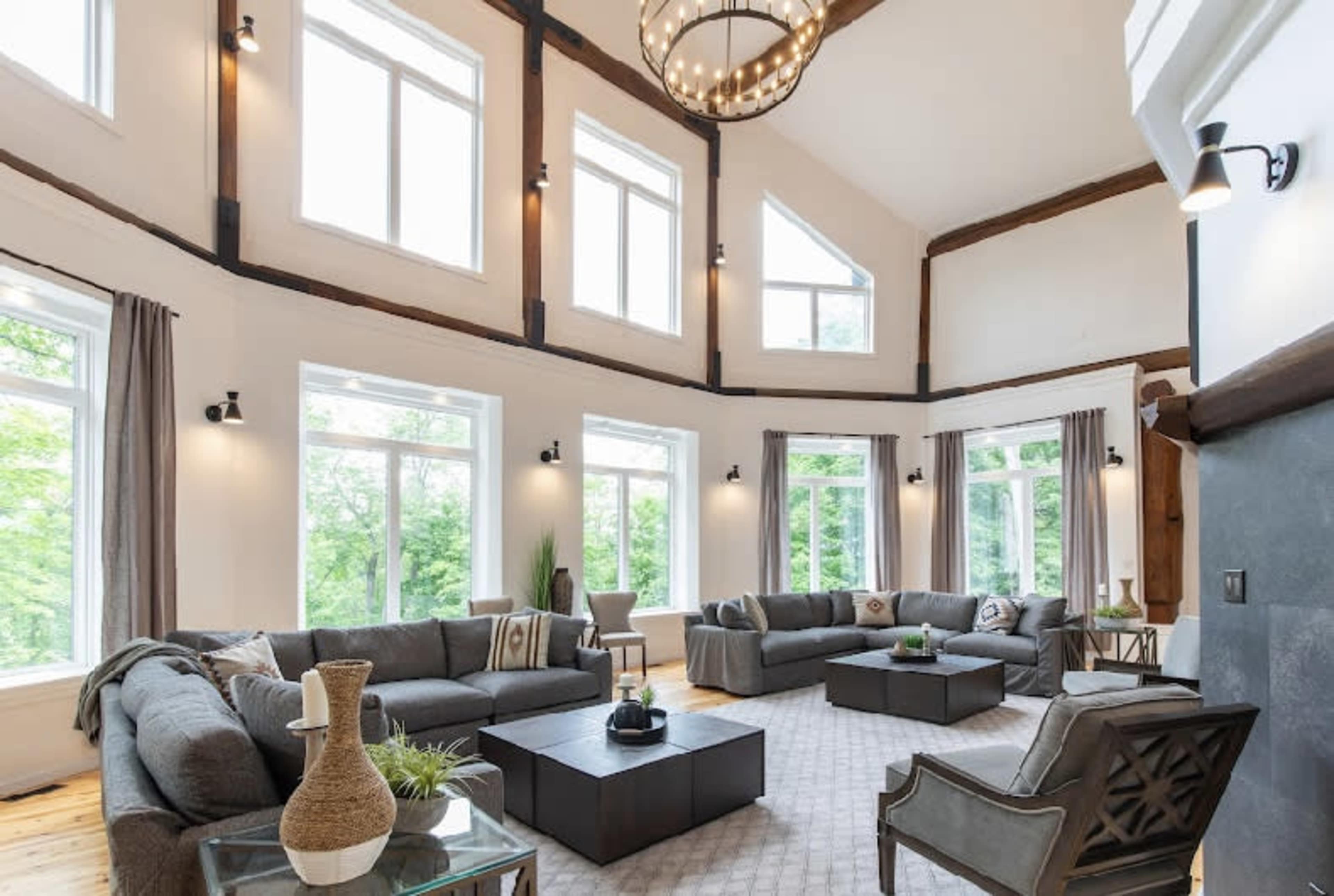 A spacious living room with large windows, multiple seating areas, and a central coffee table.