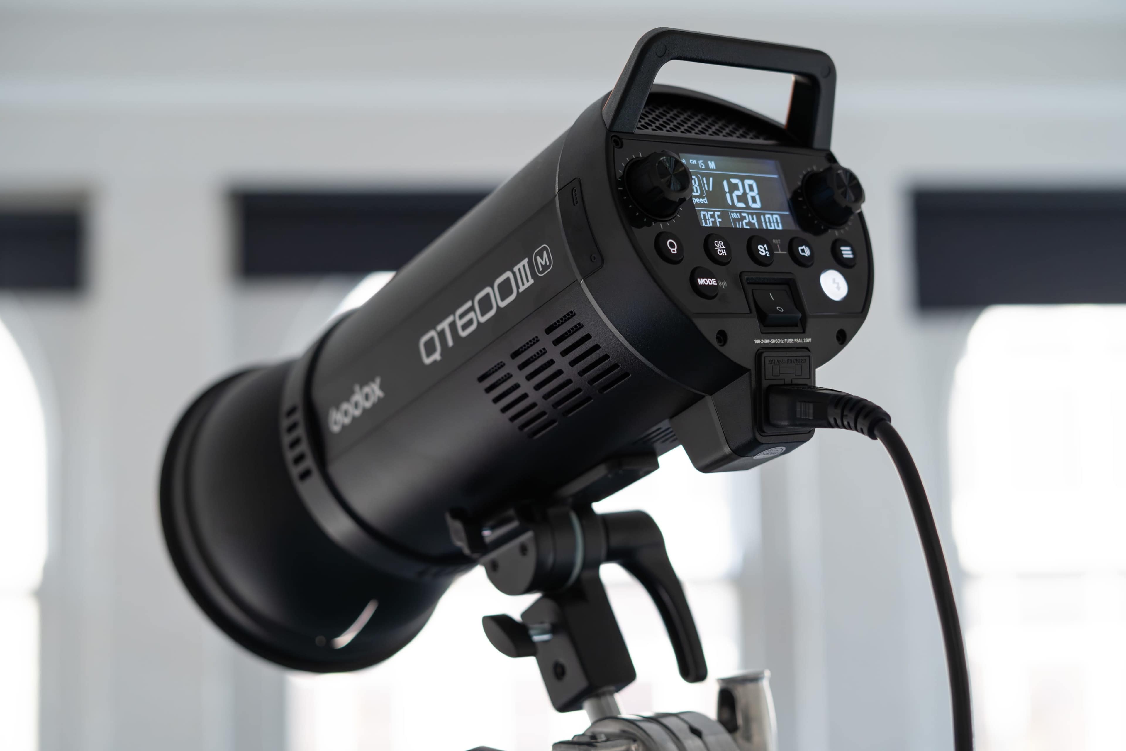 A Godox QT600II studio flash head mounted on a stand with a digital display panel.