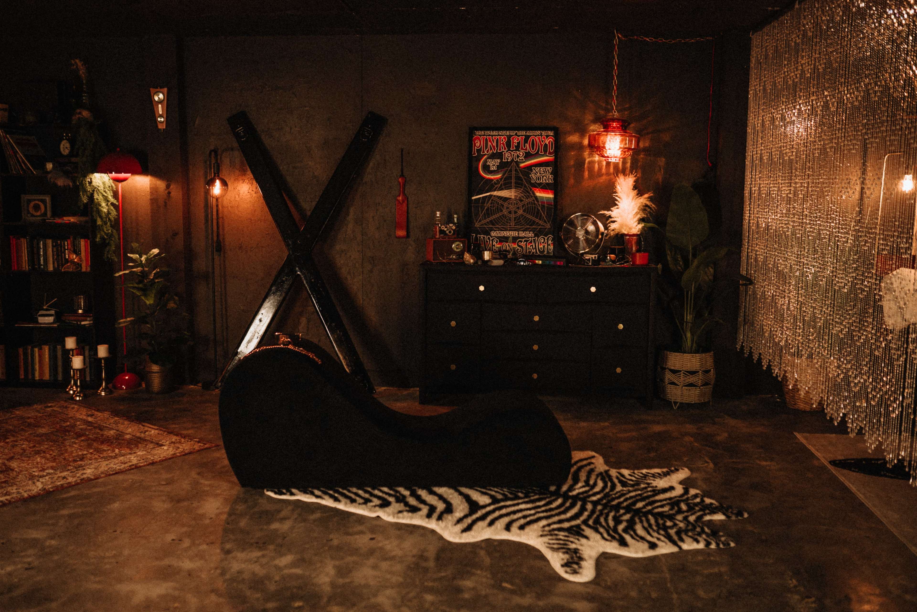 The image depicts a stylish interior space featuring a modern chaise lounge on a zebra print rug, surrounded by eclectic decorations and ambient lighting.