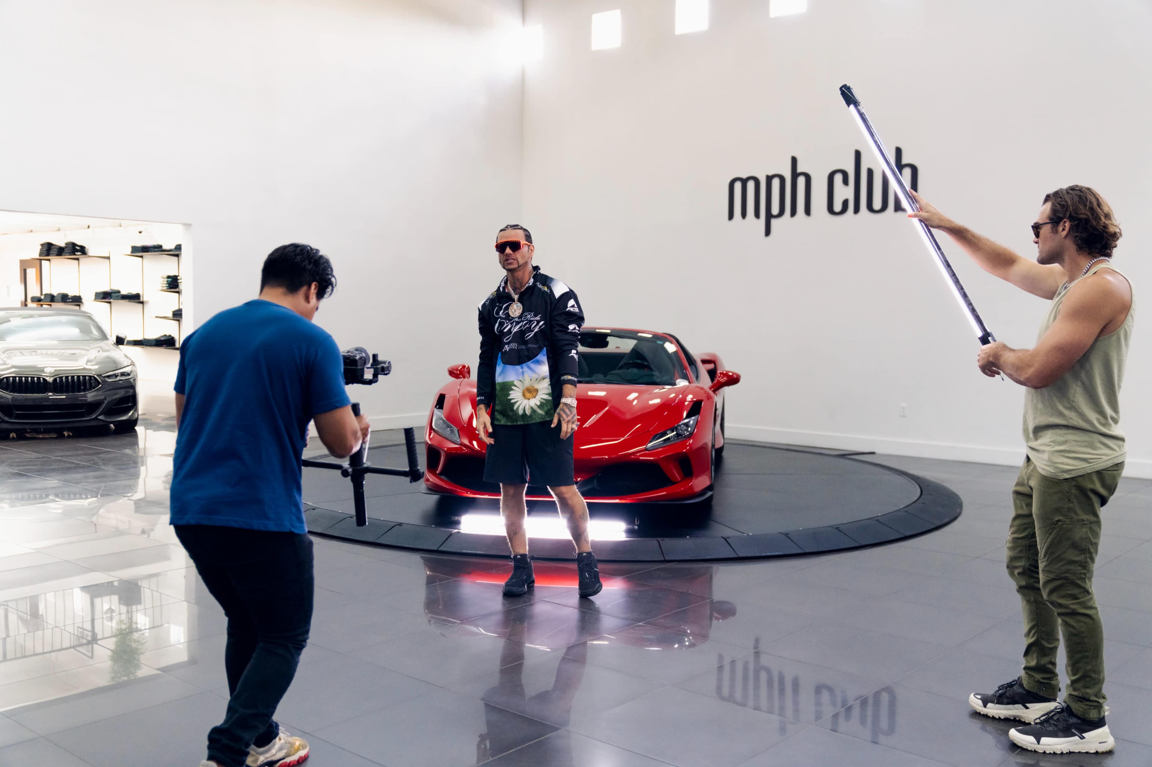 A photoshoot is taking place in a luxury car showroom featuring a red sports car.