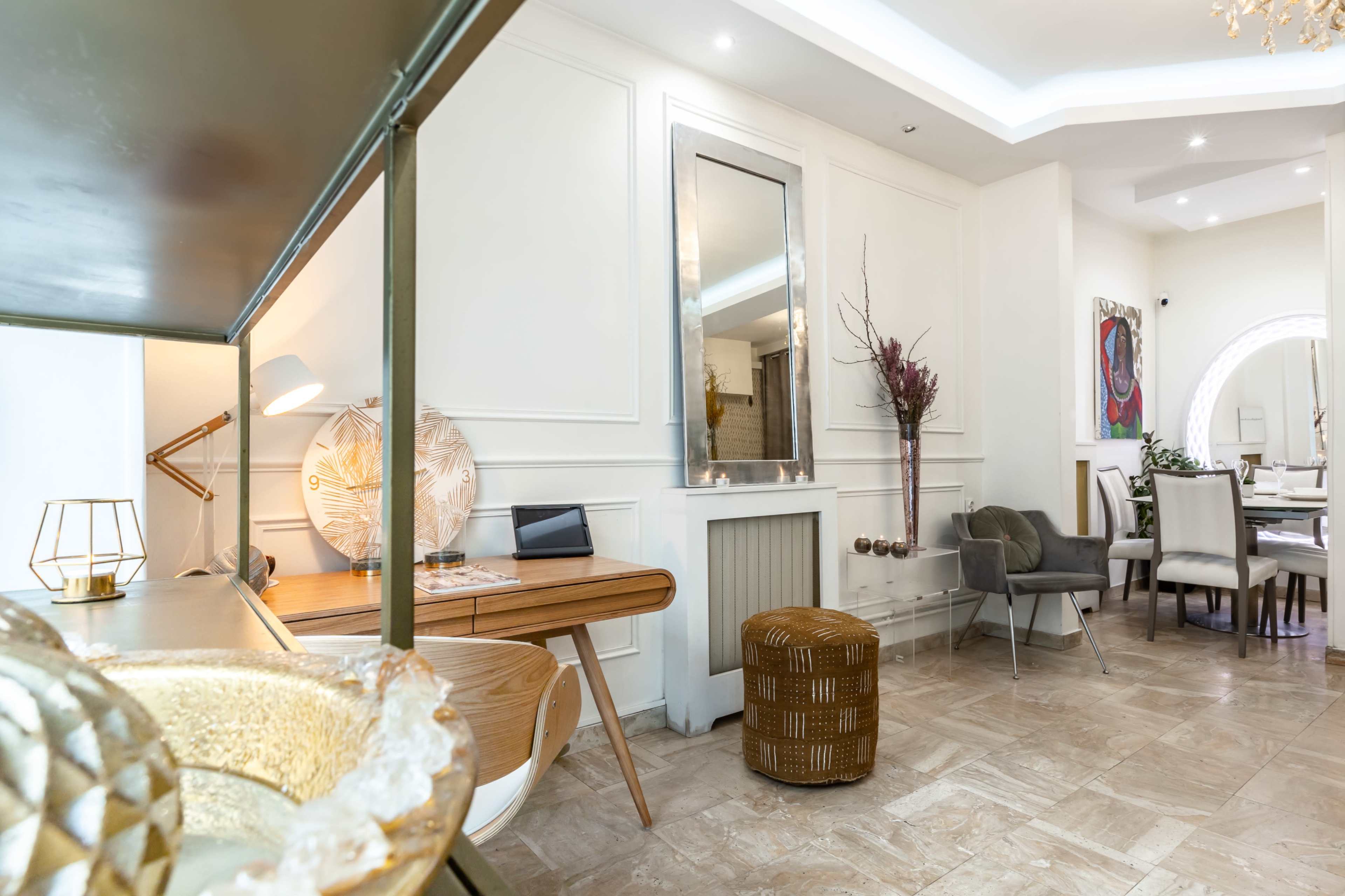 The image shows an interior space featuring a mix of modern and stylish furniture, with a table, mirror, and decorative items set against a light-colored wall.