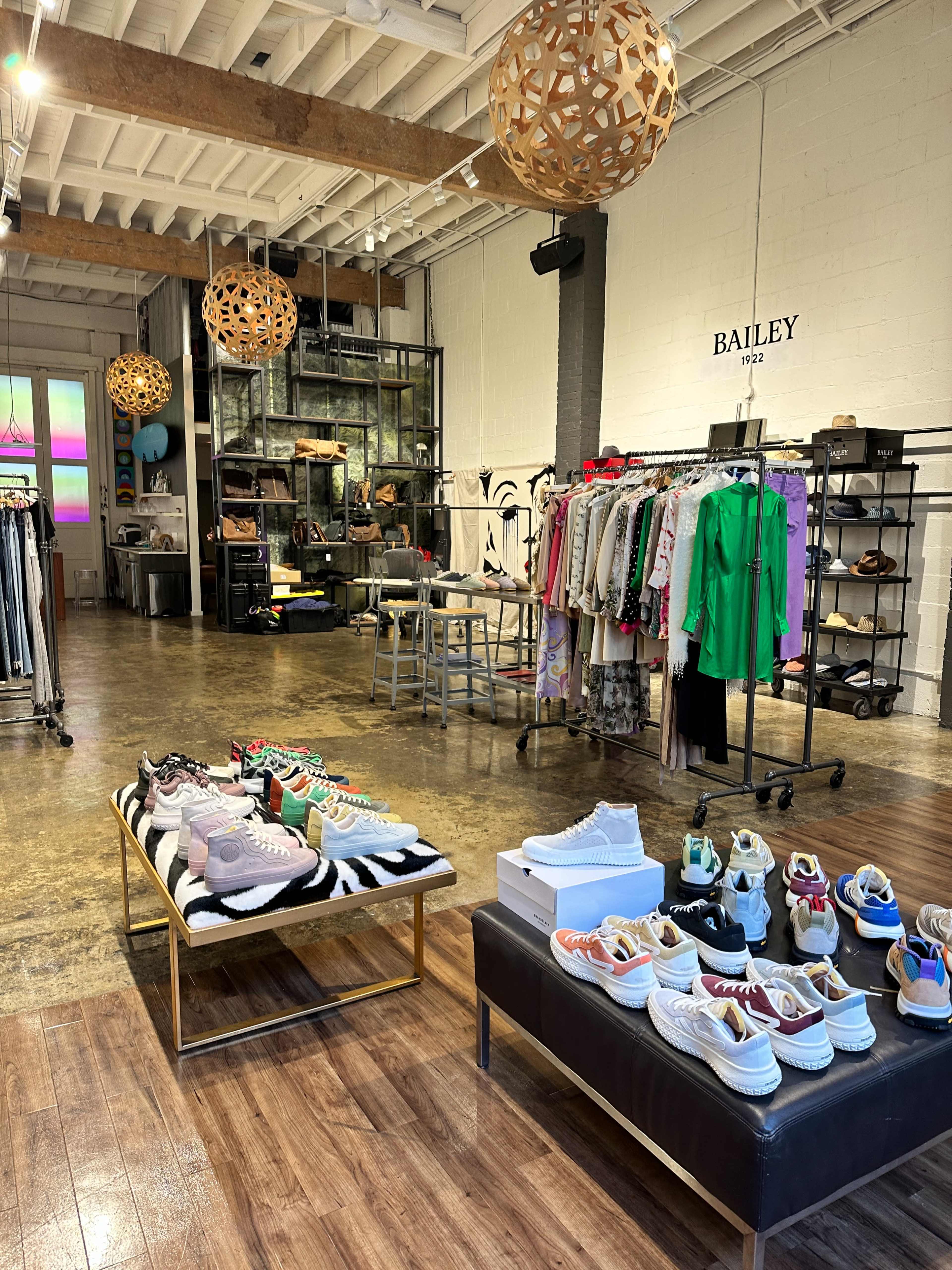 A boutique interior featuring displays of various sneakers, clothing racks, and decorative lighting.