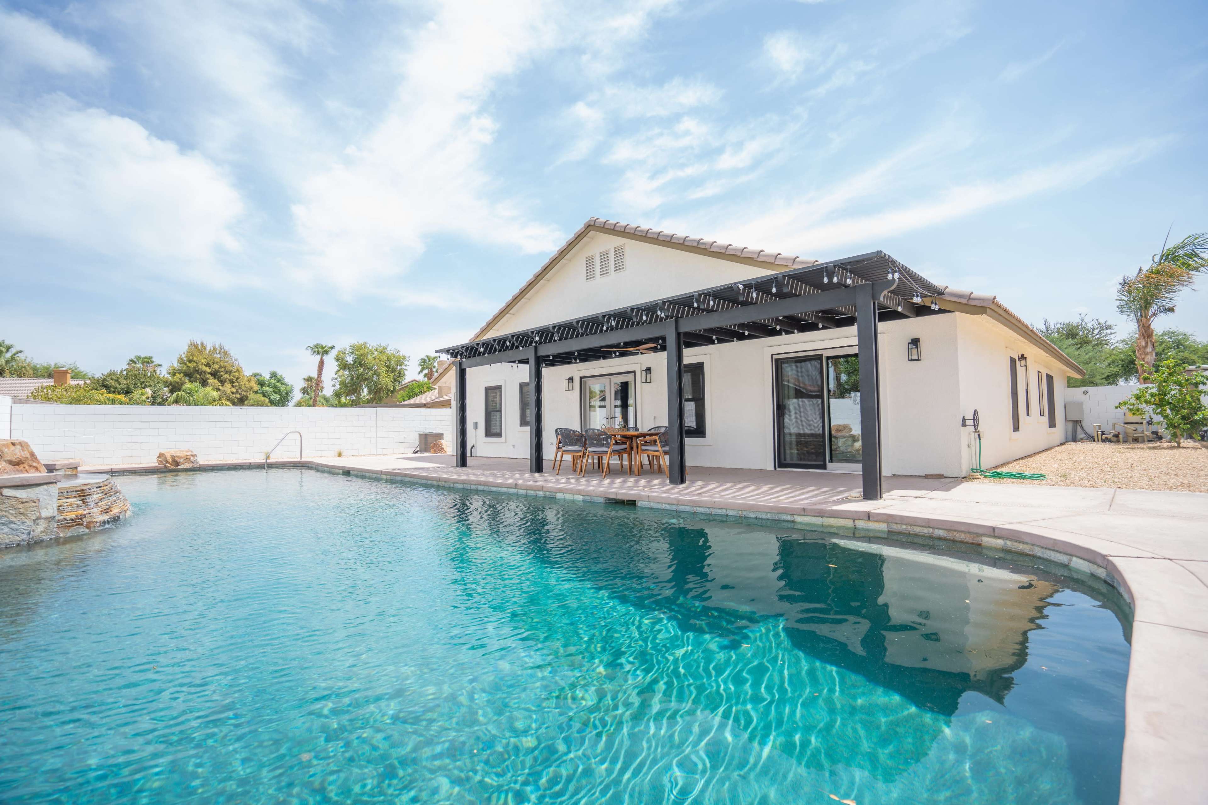 A modern house with a swimming pool and a shaded outdoor dining area.
