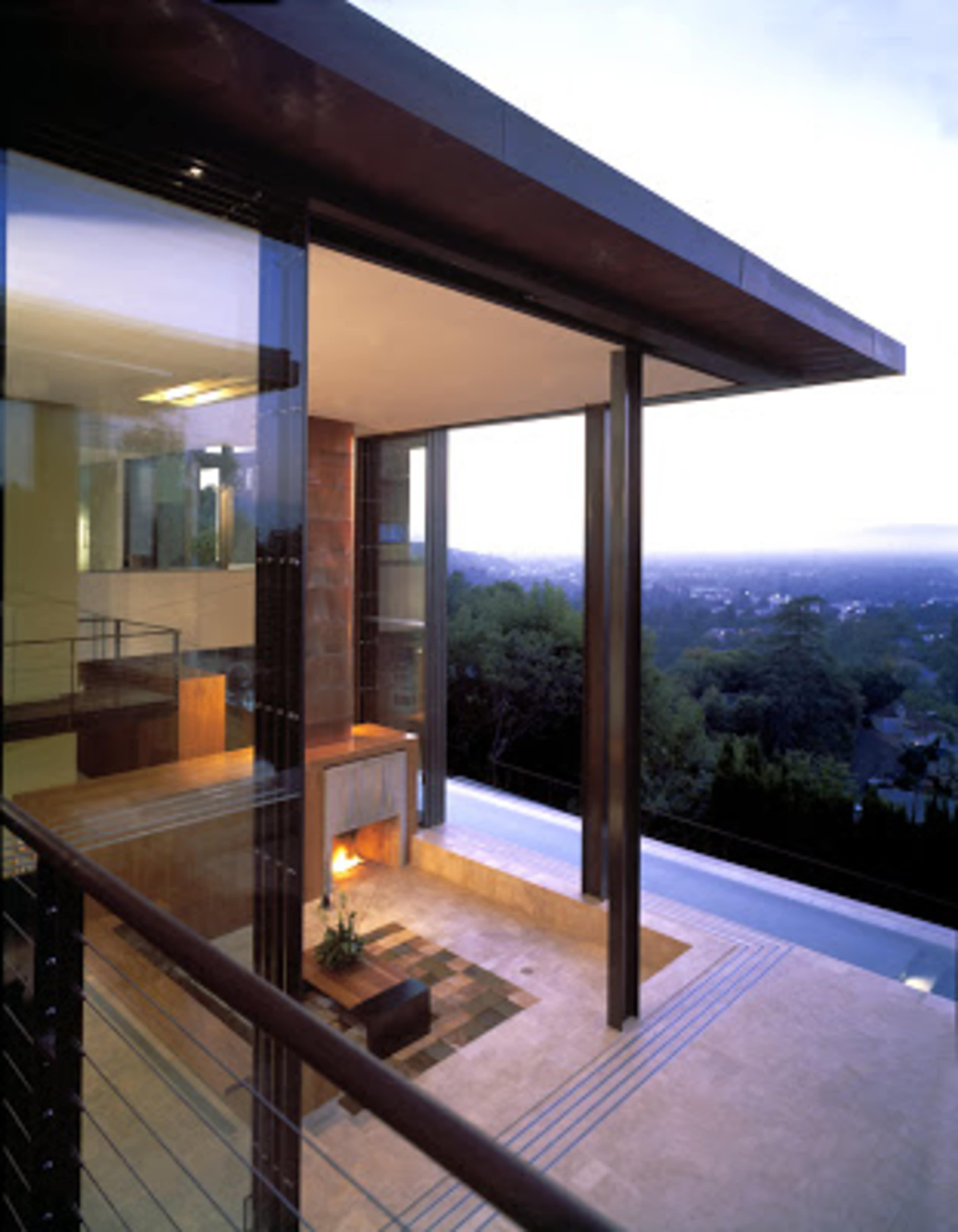 A modern house with large glass walls, a spacious interior, and a view of the landscape beyond.