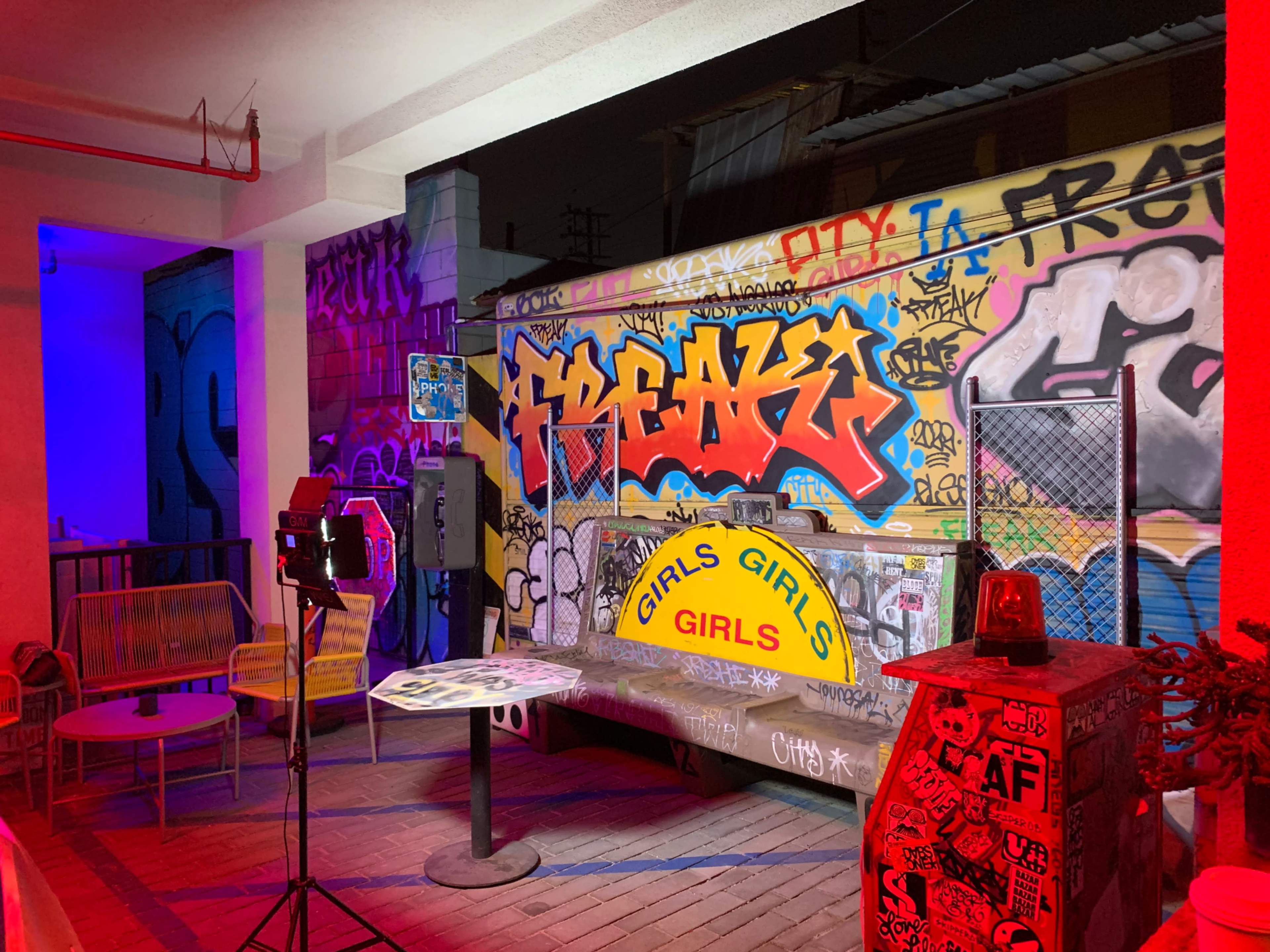 The scene shows a graffiti-covered outdoor area with a table and a sign that reads "GIRLS GIRLS GIRLS."