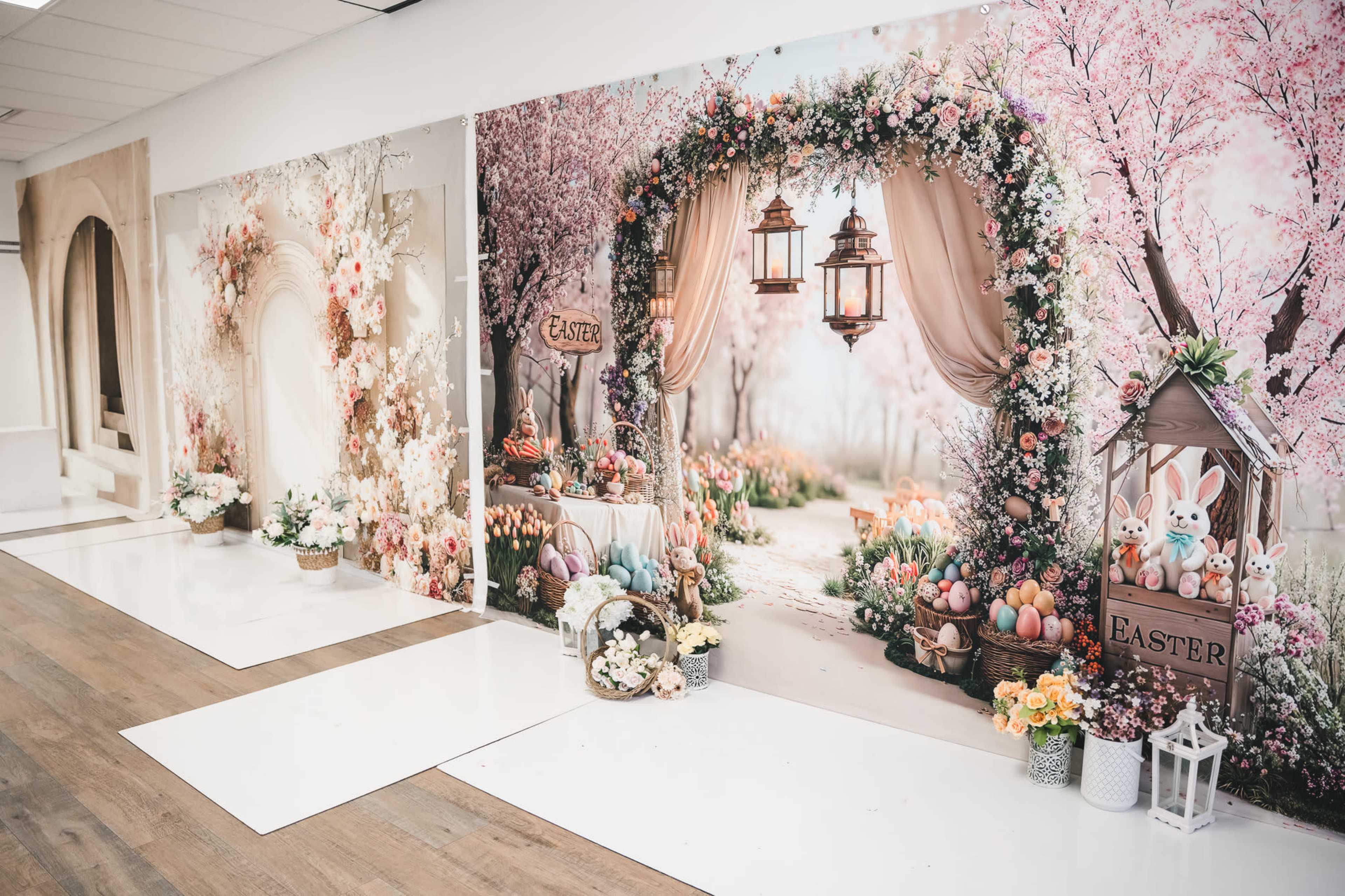 The image shows a studio space featuring three large, themed backdrops decorated with floral designs and Easter elements, including bunnies and colorful eggs.