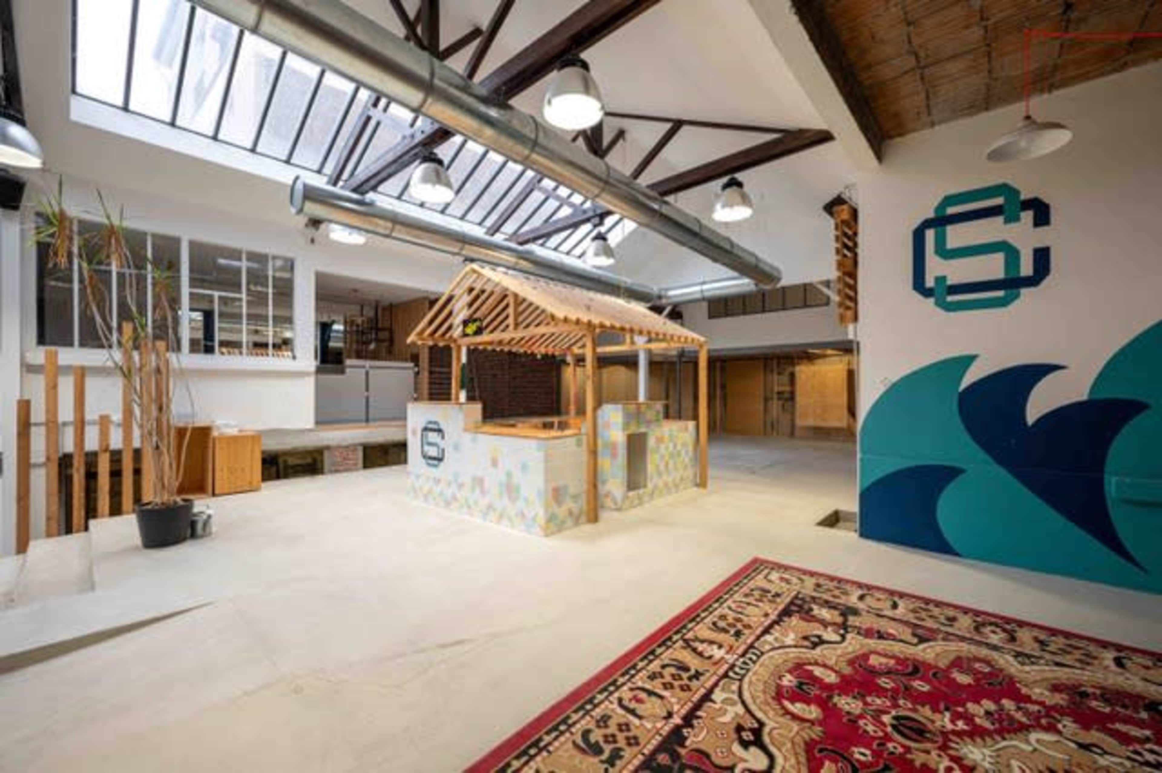 A spacious indoor area featuring a wooden structure resembling a kiosk, surrounded by open spaces and decorative elements.