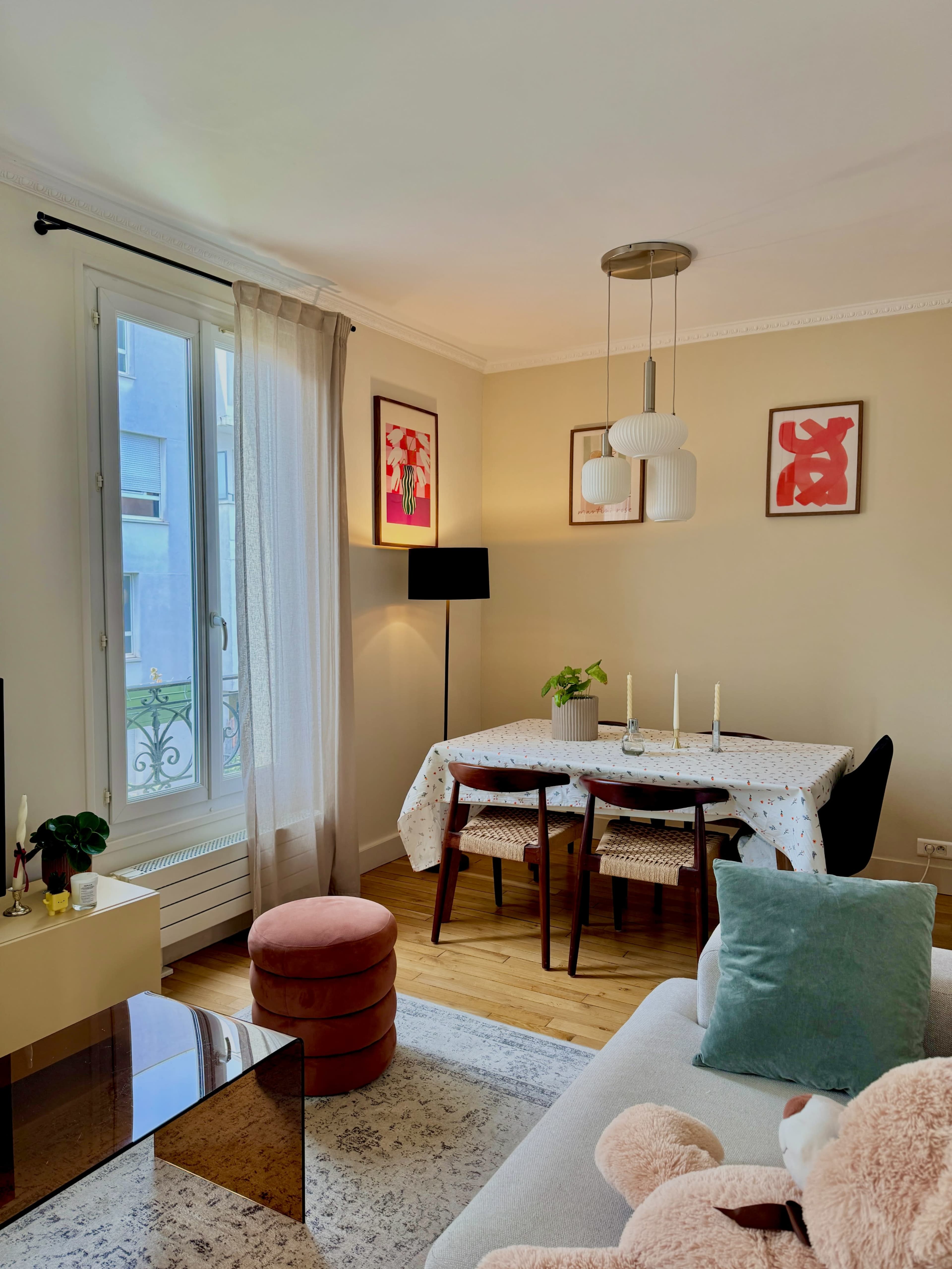 The image shows a cozy living room with a dining area featuring a table, chairs, and decorative wall art.