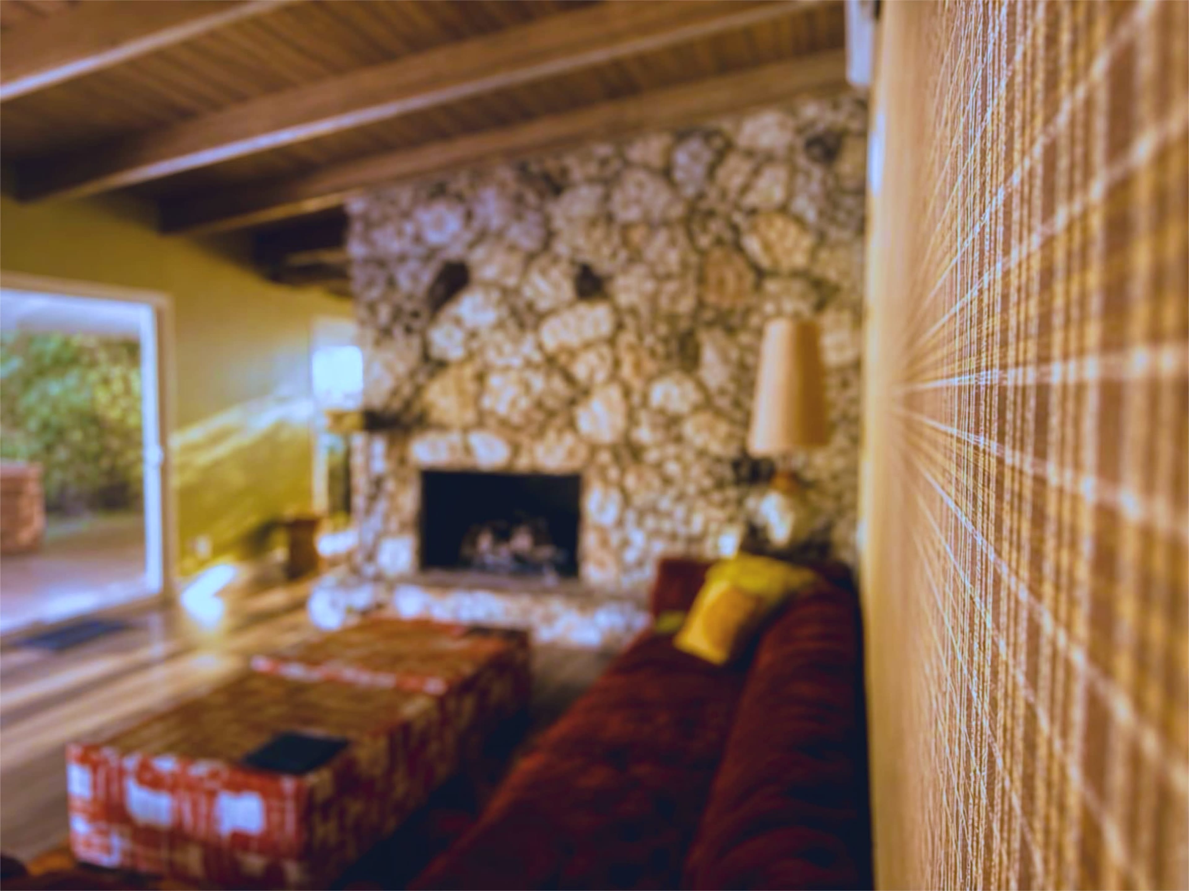 The image shows a living room featuring a stone fireplace, a red sofa, and a textured wall.