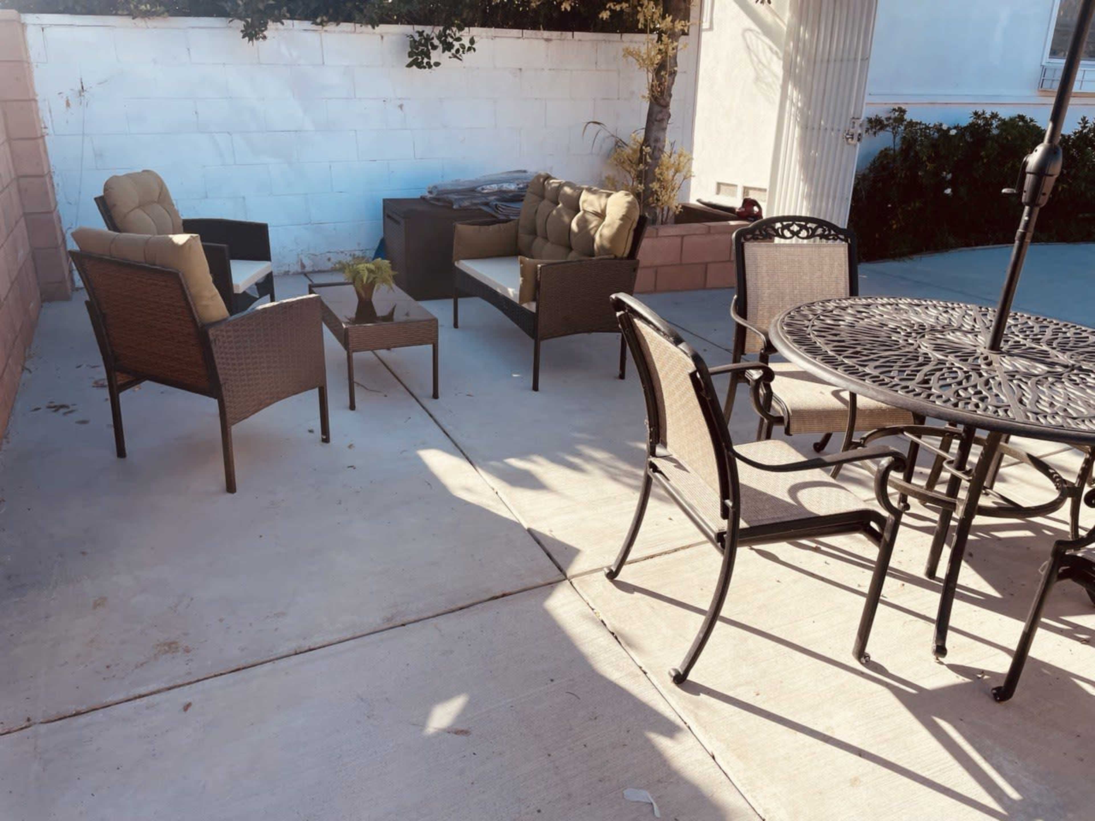 A patio area features several outdoor seating arrangements, including cushioned chairs and a dining table with metal chairs.