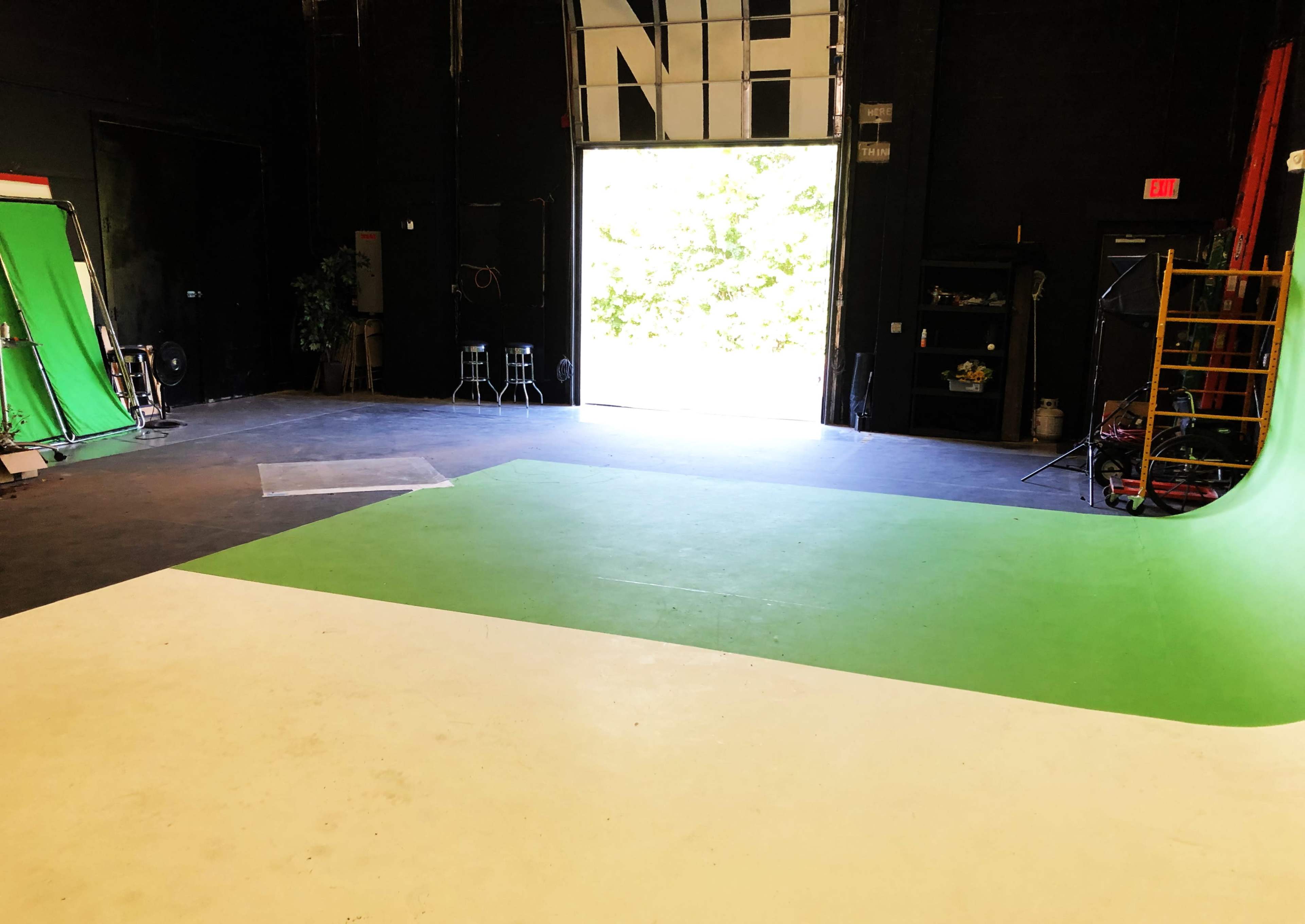 A film studio with green screens and an open door leading outside.