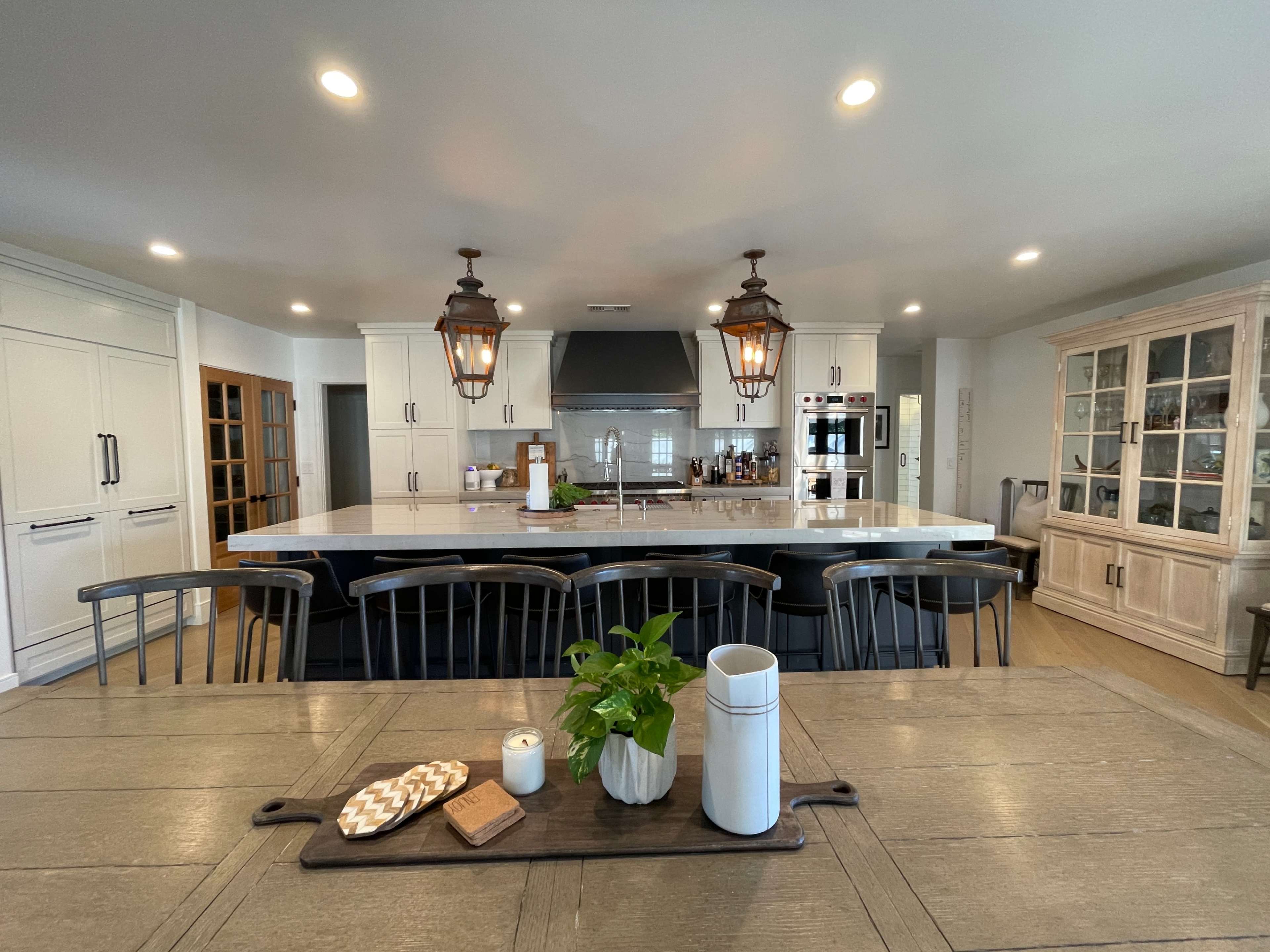 A modern kitchen with a large island, pendant lights, and a dining table set with decorative items.