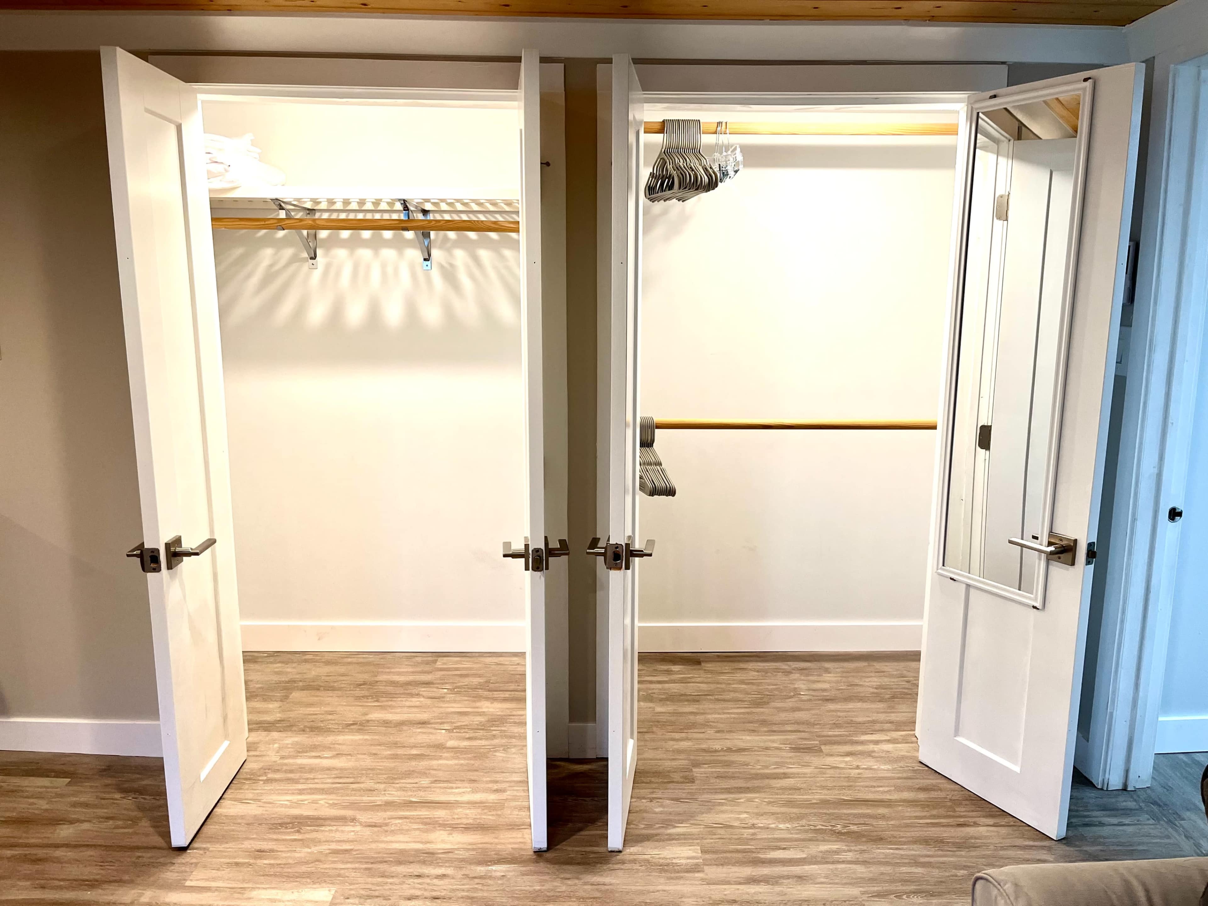 A set of double doors opening to a spacious, empty closet with a hanging rod and a shelf above.