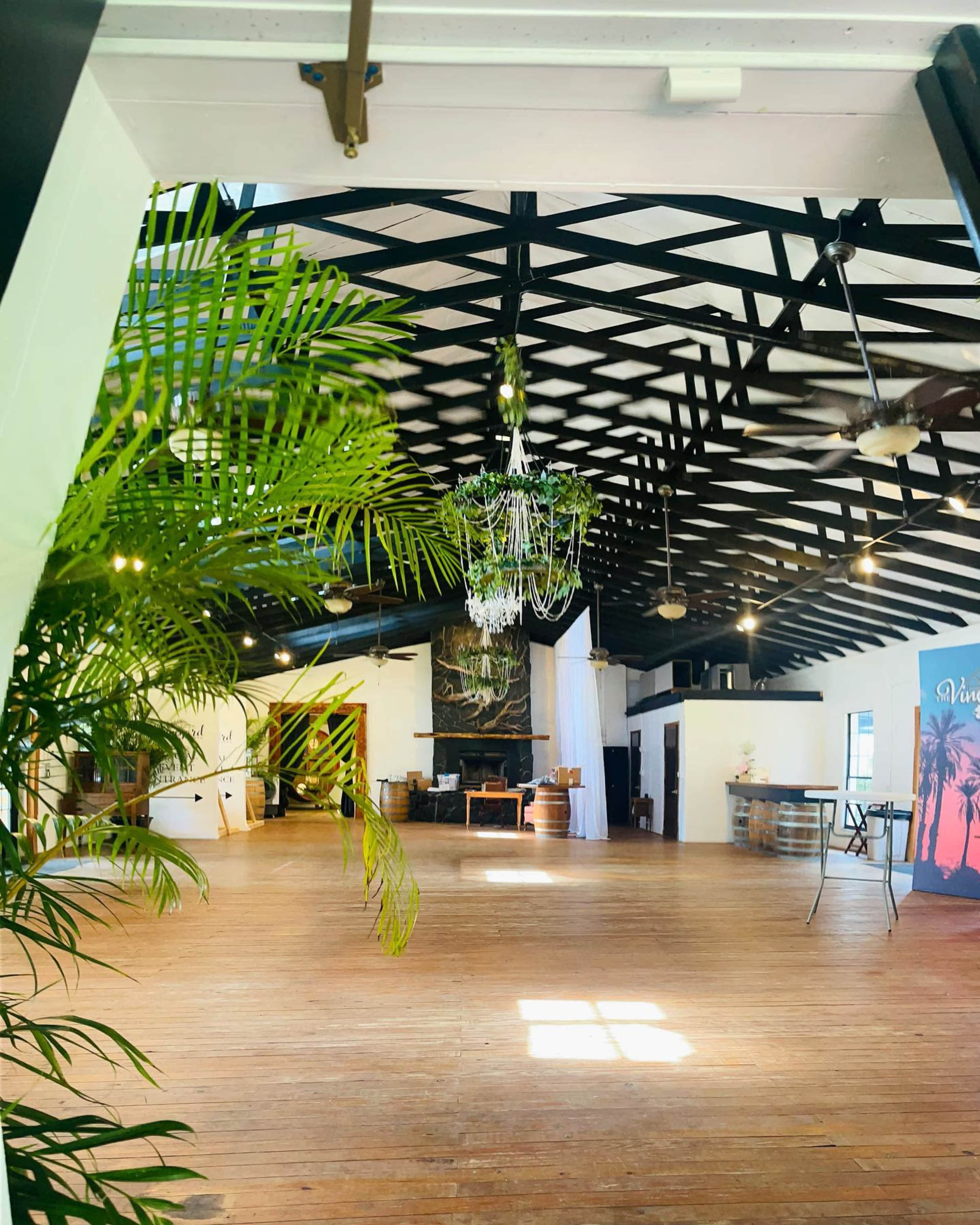 The image shows a spacious indoor venue with high ceilings, wooden floors, and large windows allowing natural light to enter.