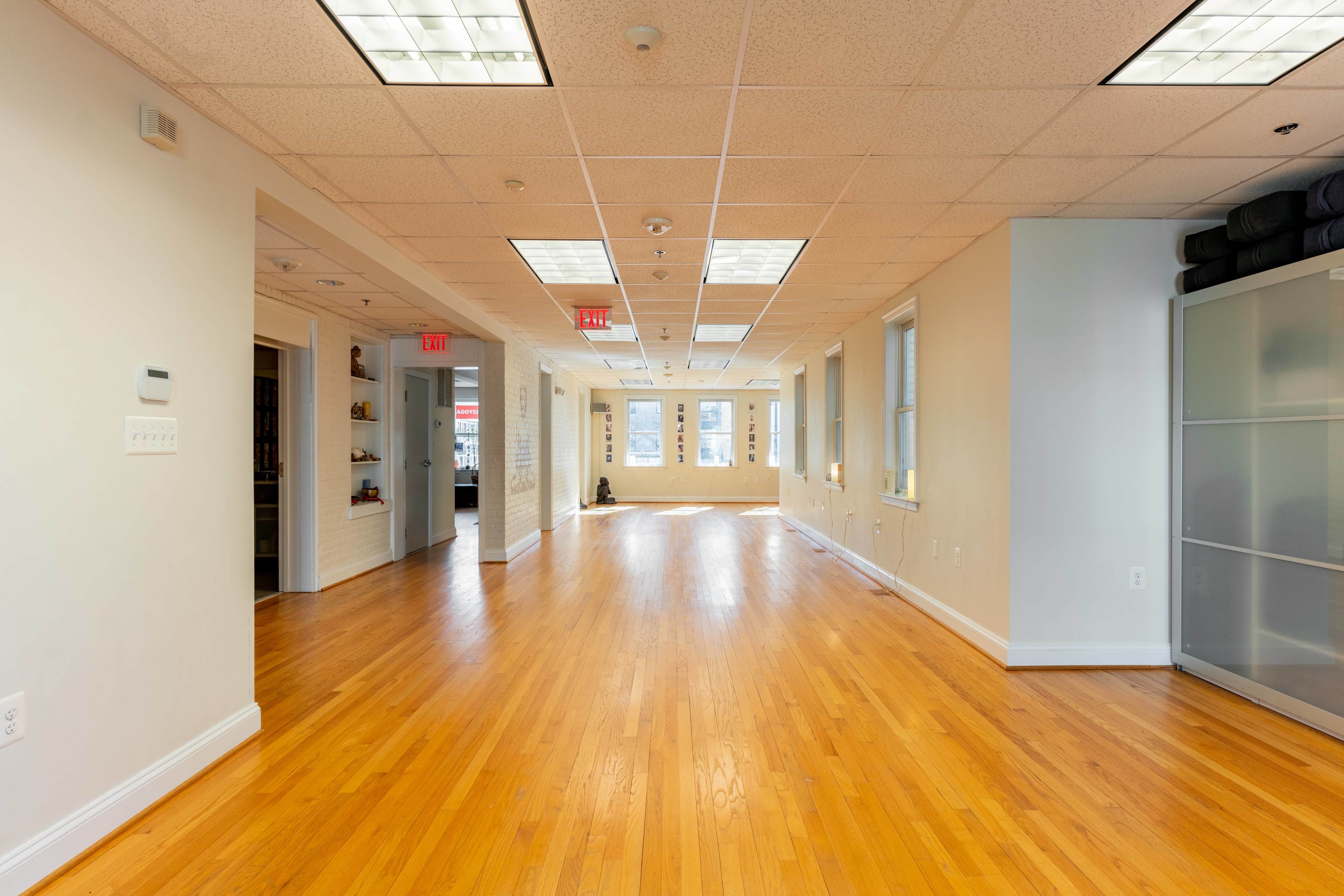 A long, narrow corridor in an office building with wooden floors and multiple doors leading to adjacent rooms.