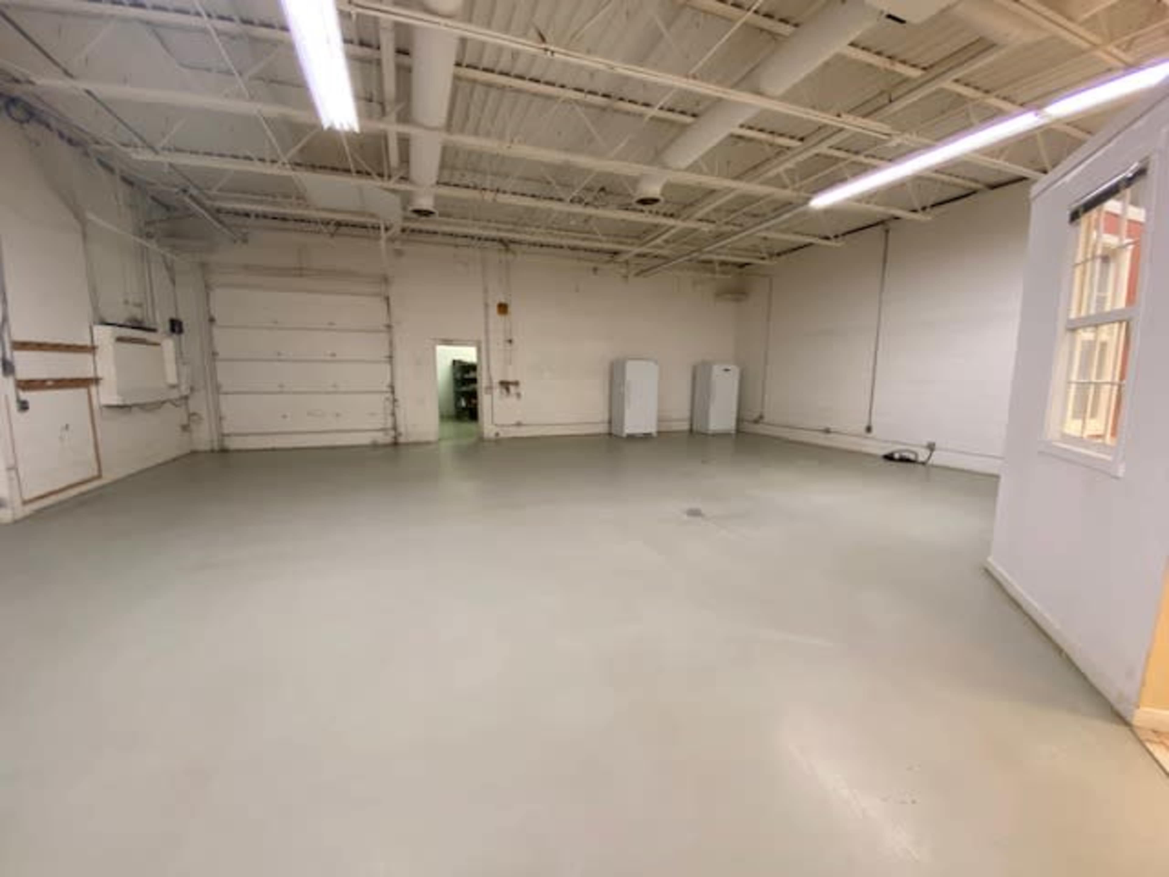 A large, empty commercial space with a smooth, light-colored floor and minimal fixtures.