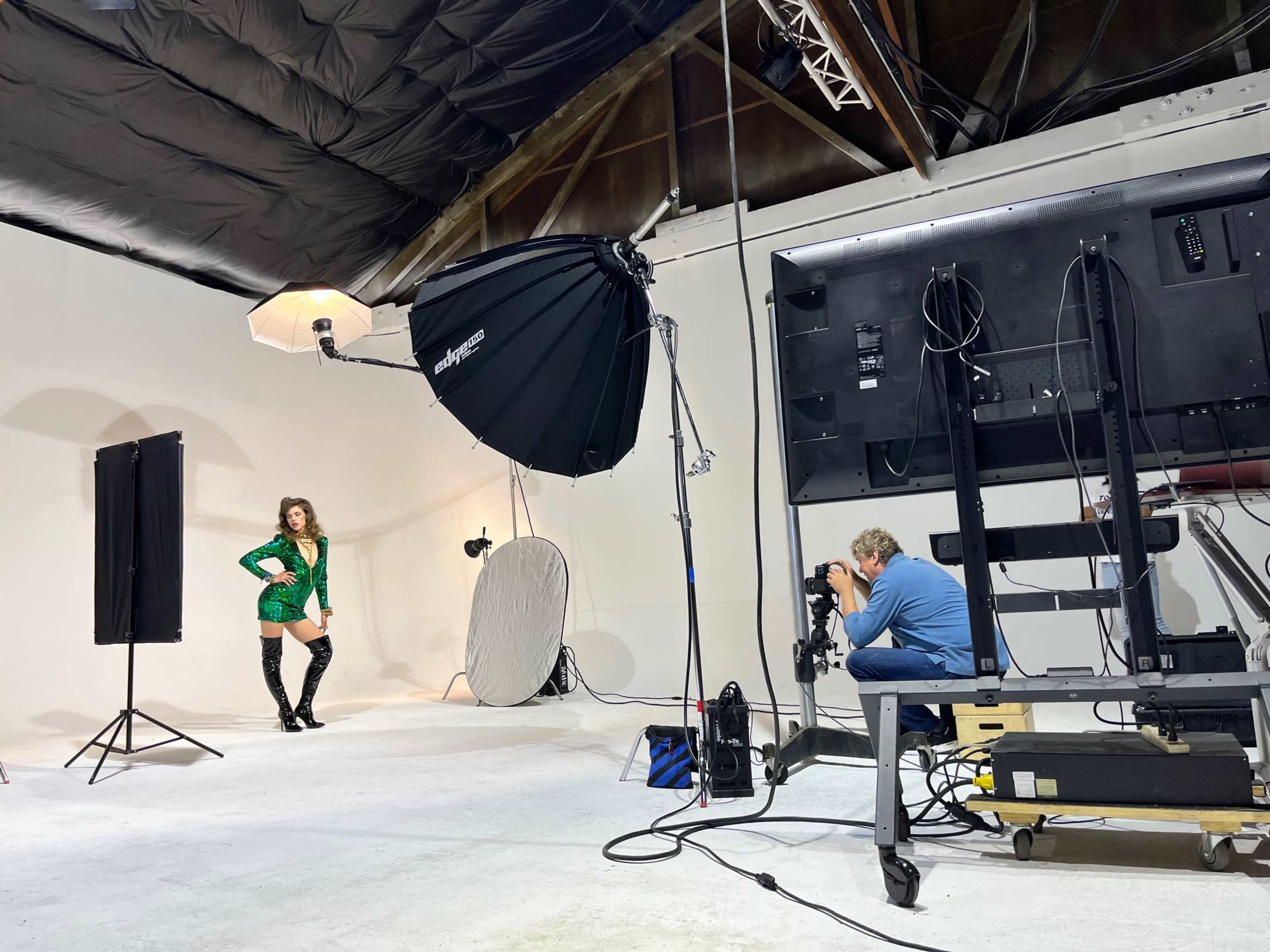 A photographer captures a model posing in a studio setting with professional lighting equipment.