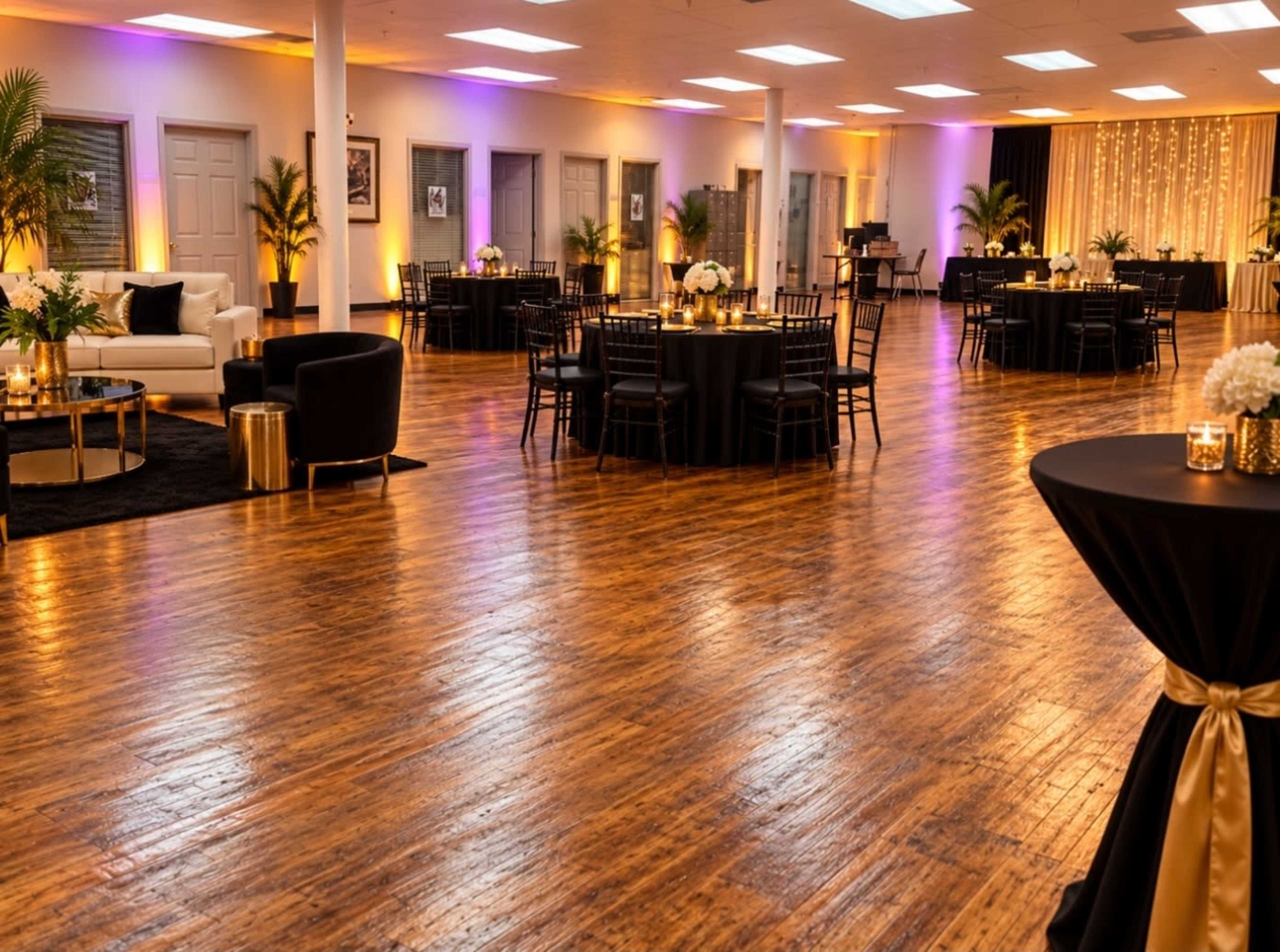 The image shows a spacious event venue with wooden floors, elegantly arranged tables, and decorative lighting.
