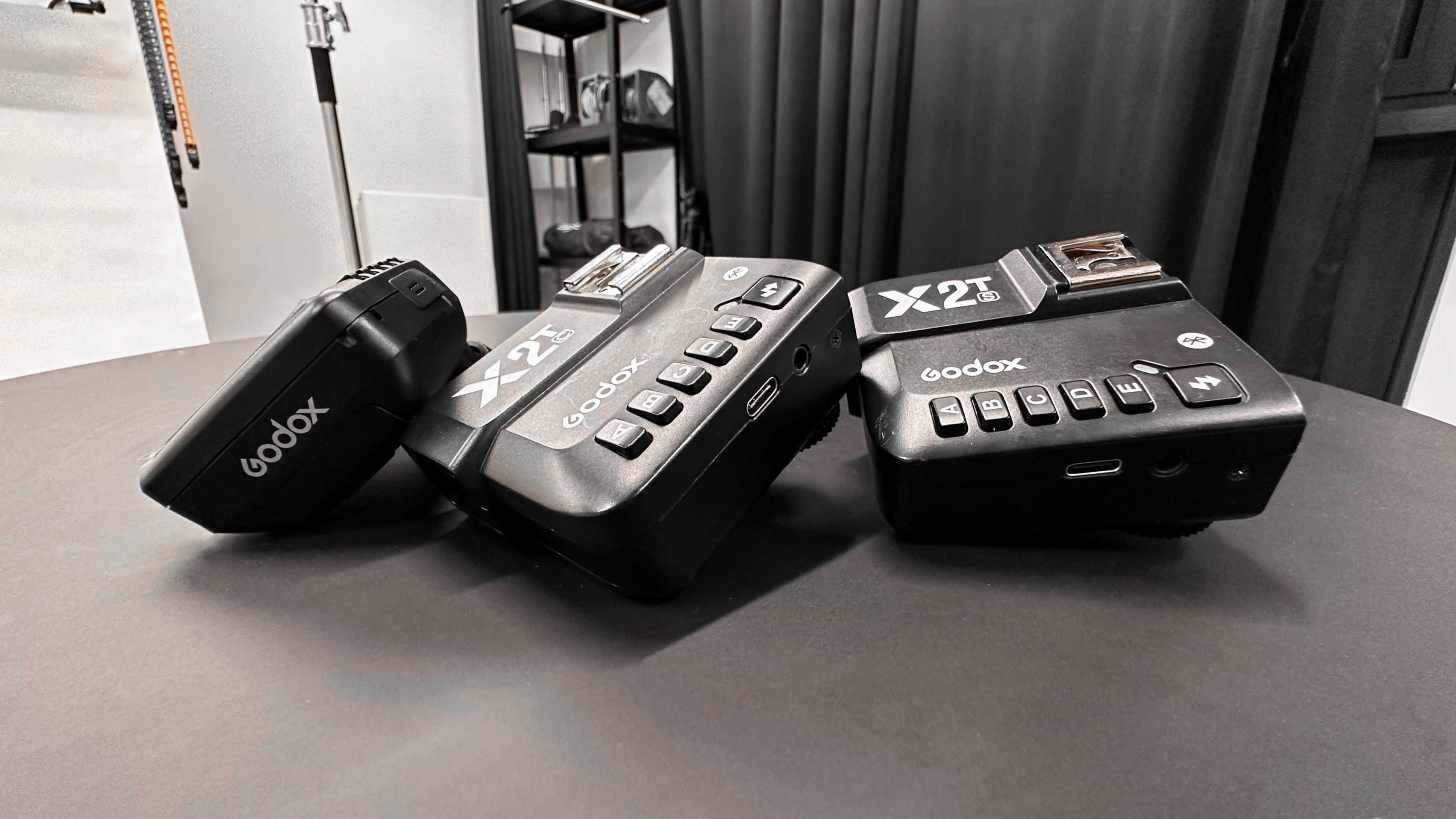 Two Godox X2T flash trigger units positioned on a black surface.