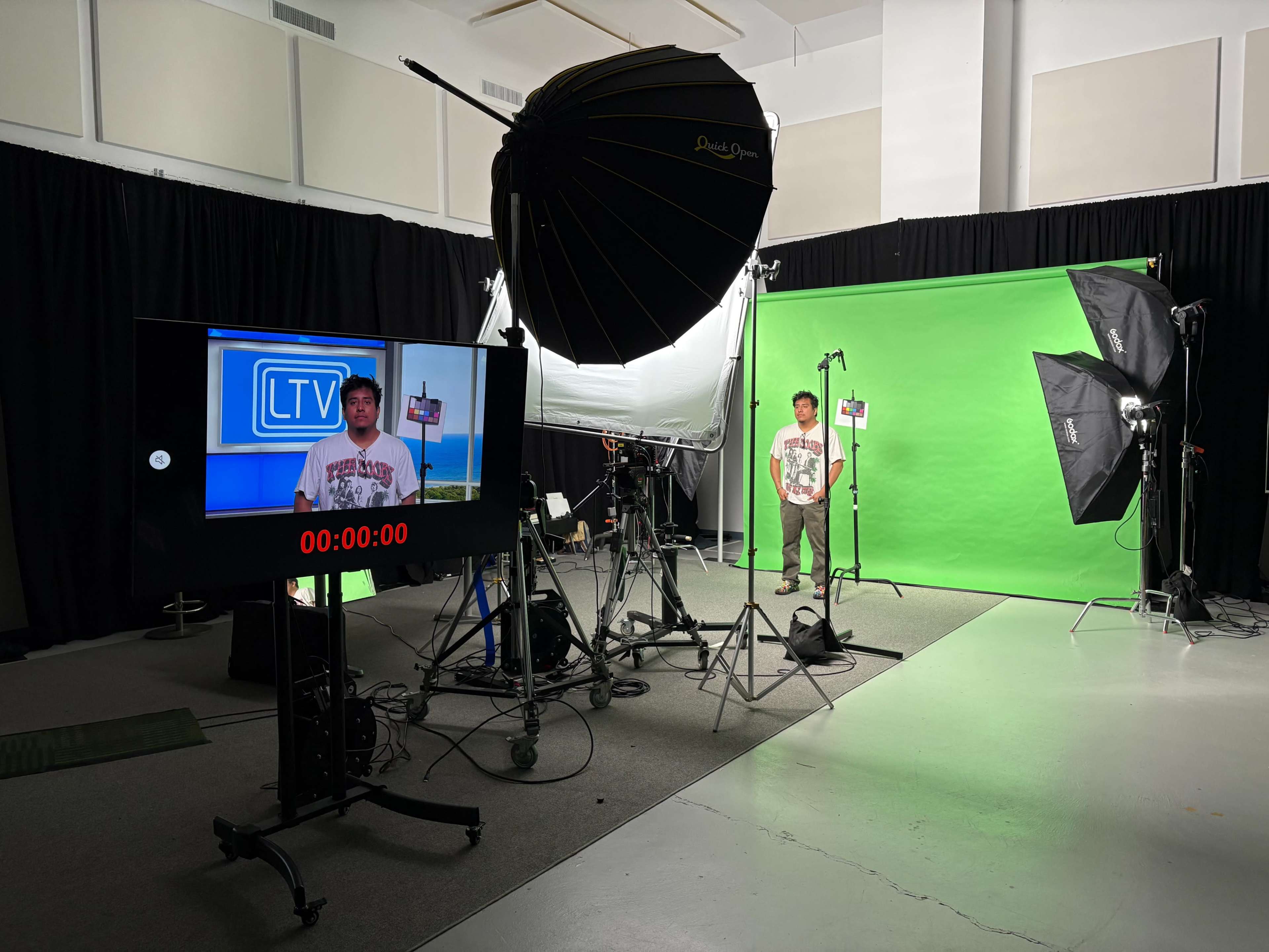 A television studio setup features a person on a green screen background, surrounded by lighting equipment and a monitor displaying a countdown.