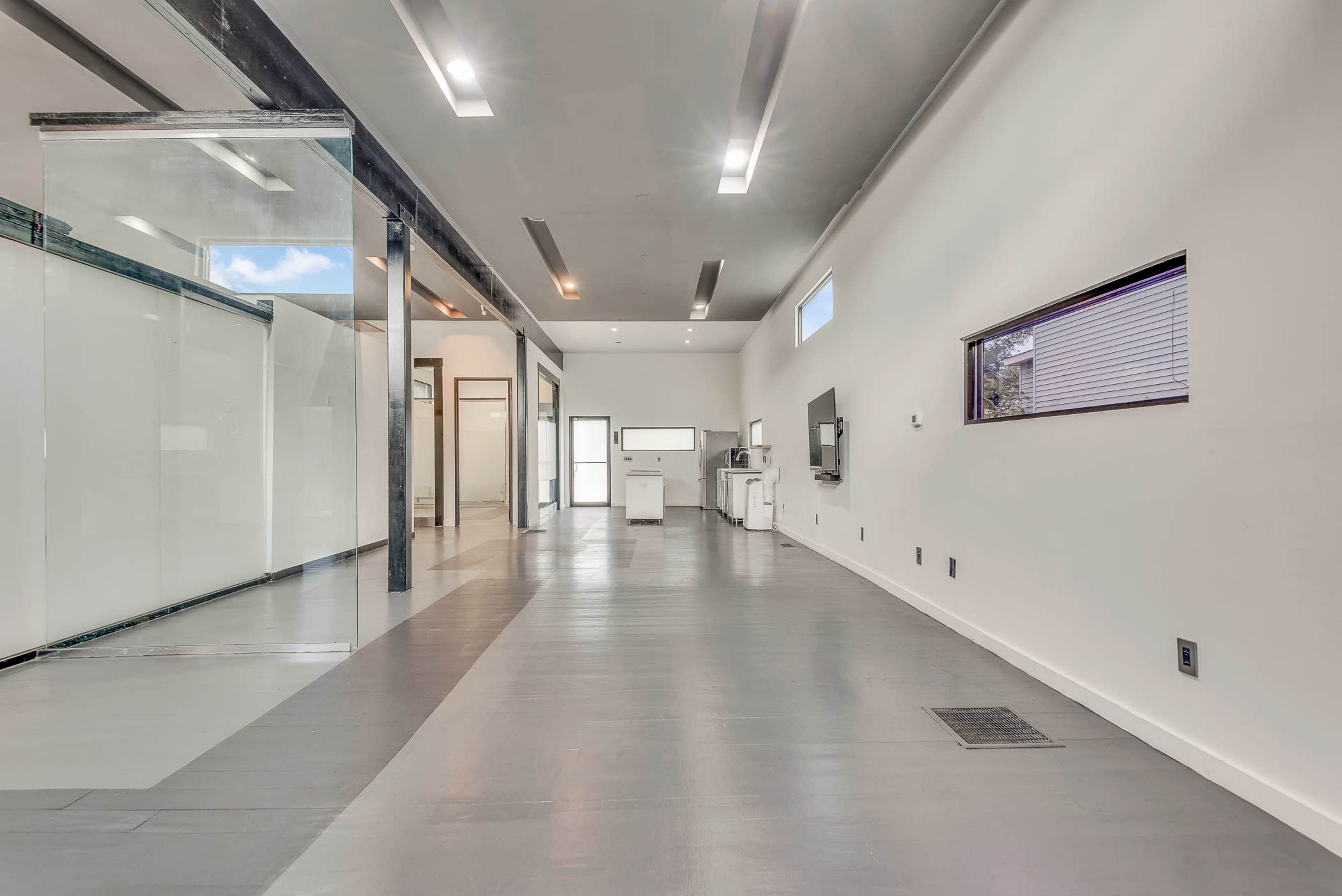 The image shows a spacious, modern interior with sleek flooring and glass partitions.