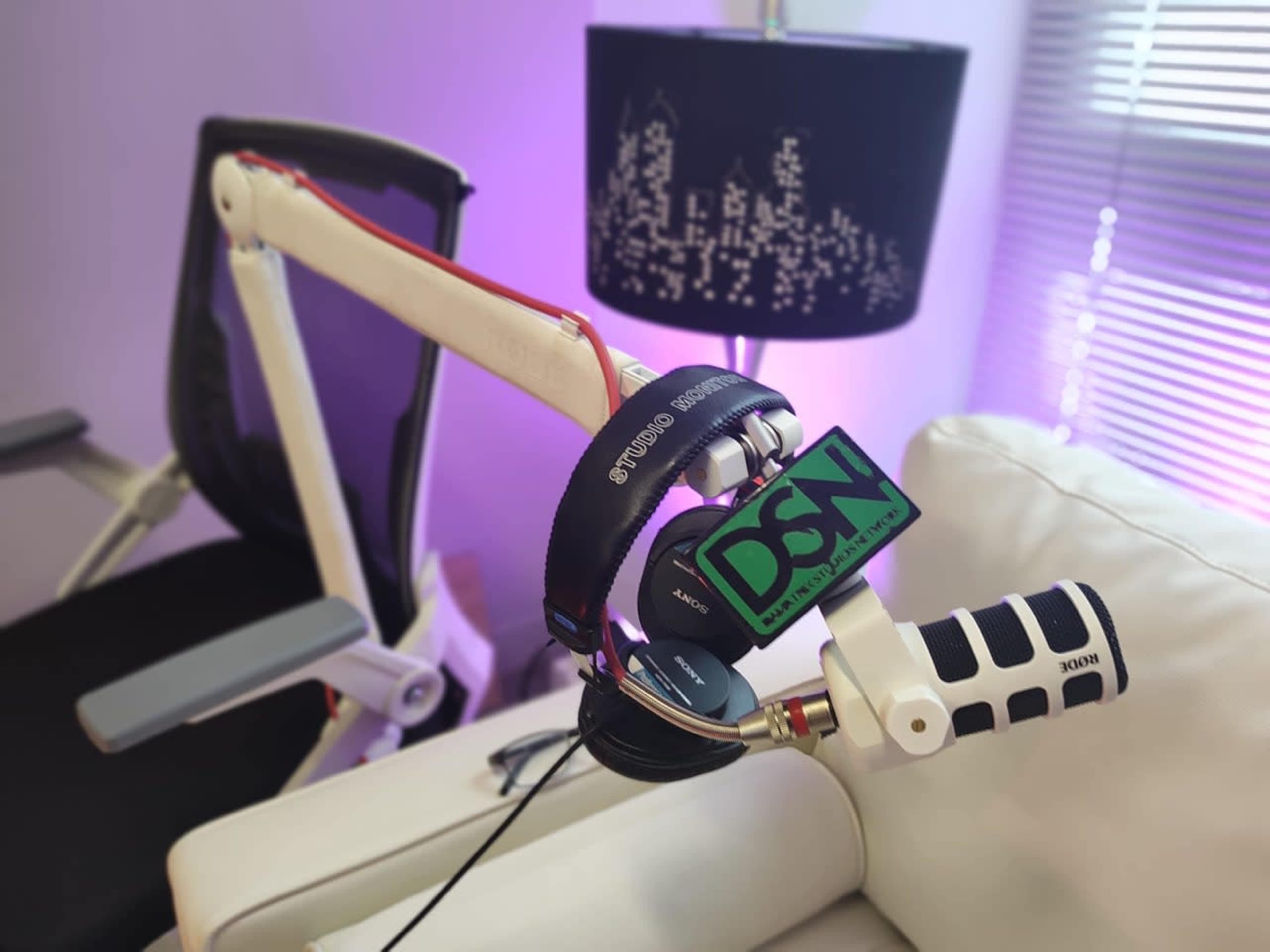 A microphone with a headset is resting on a white armchair beside a lamp with a city skyline design.