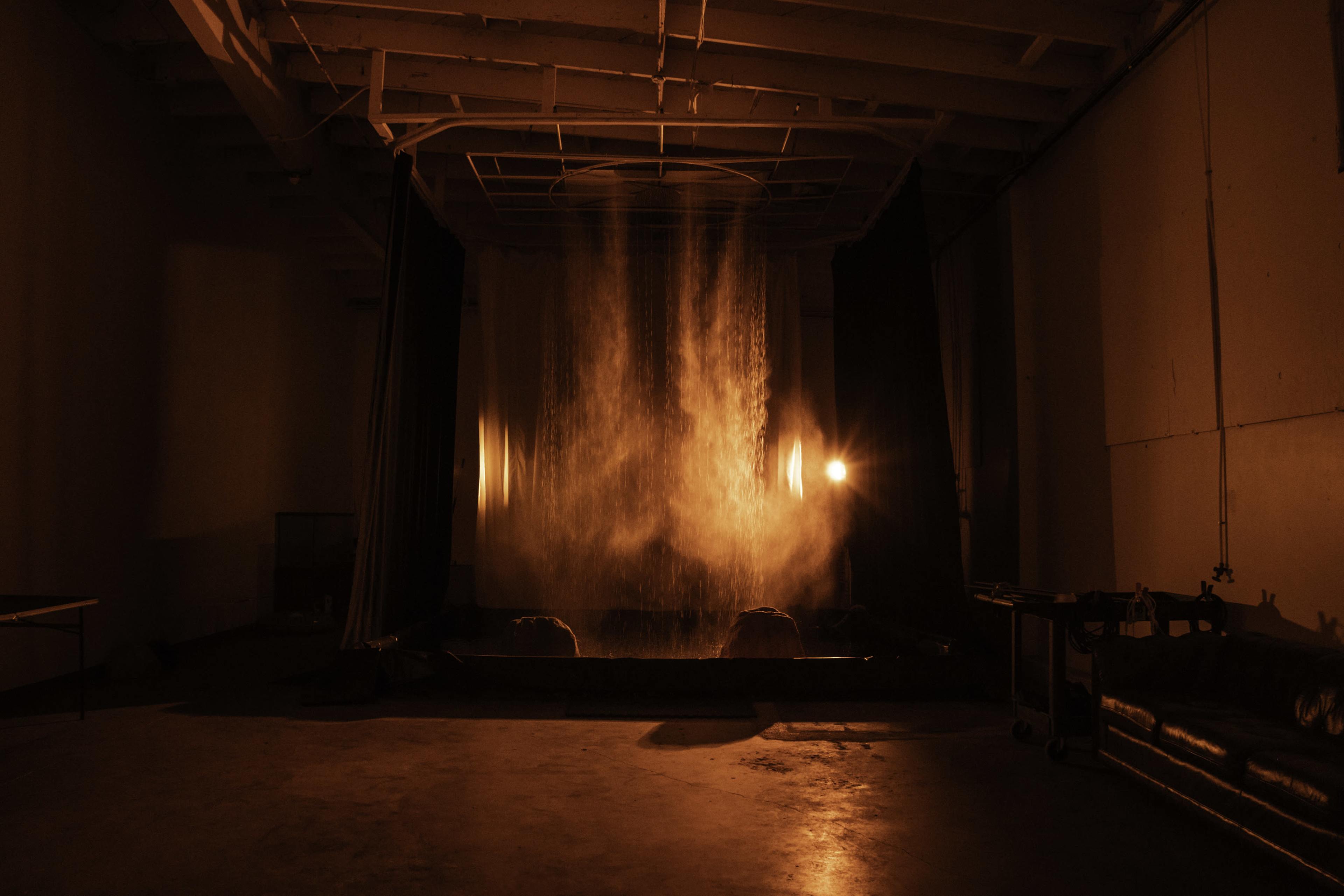 A large water feature produces a cascading flow in a dimly lit room with orange lighting.