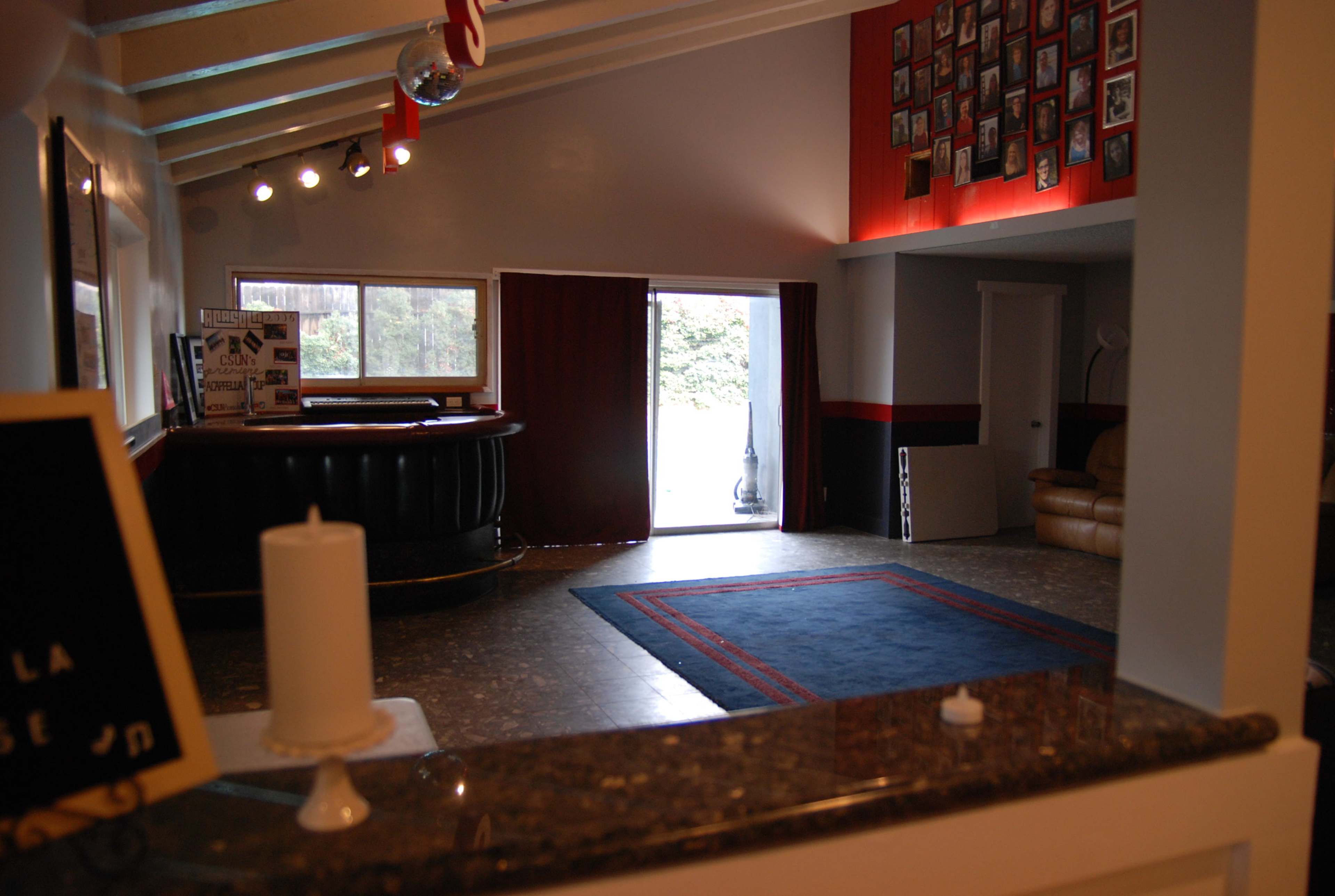 An interior room with a bar area, a patterned rug on the floor, and a large wall displaying numerous framed photos.