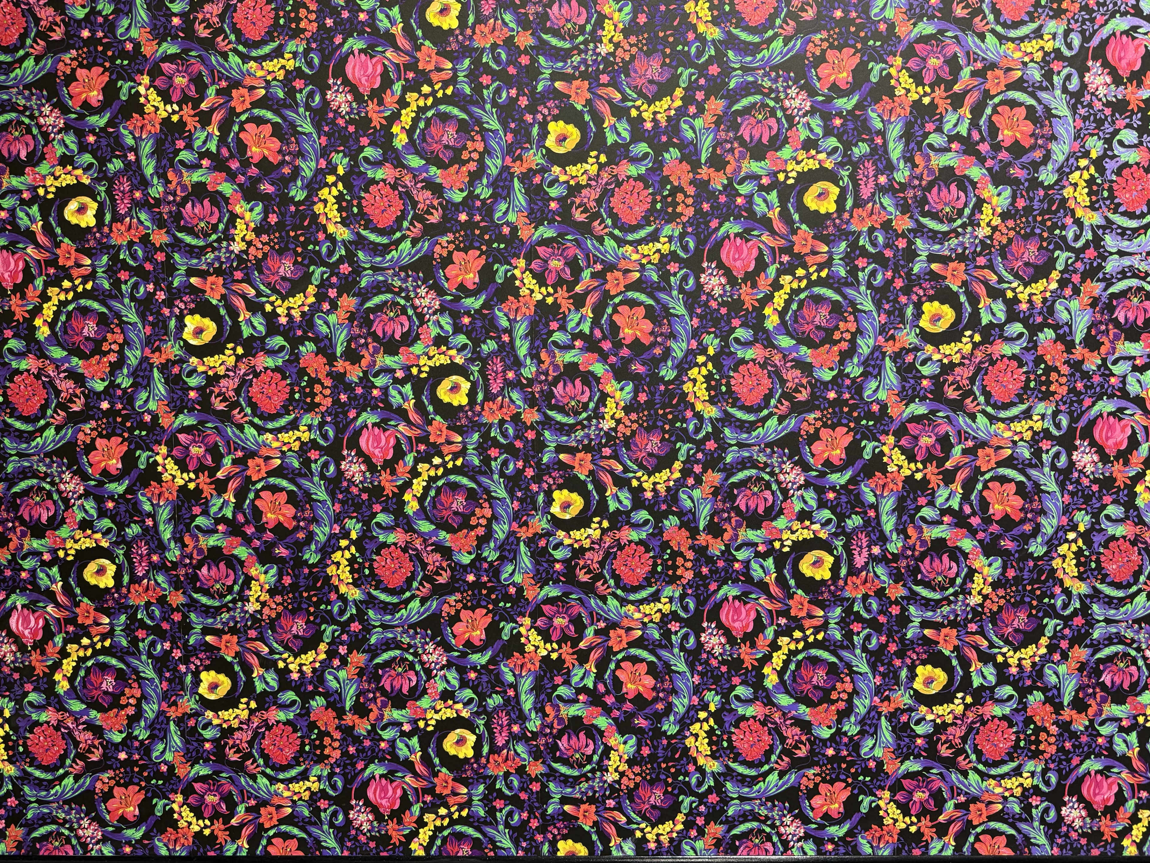 The image features a vibrant floral pattern with a variety of colorful flowers and intricate designs set against a dark background.