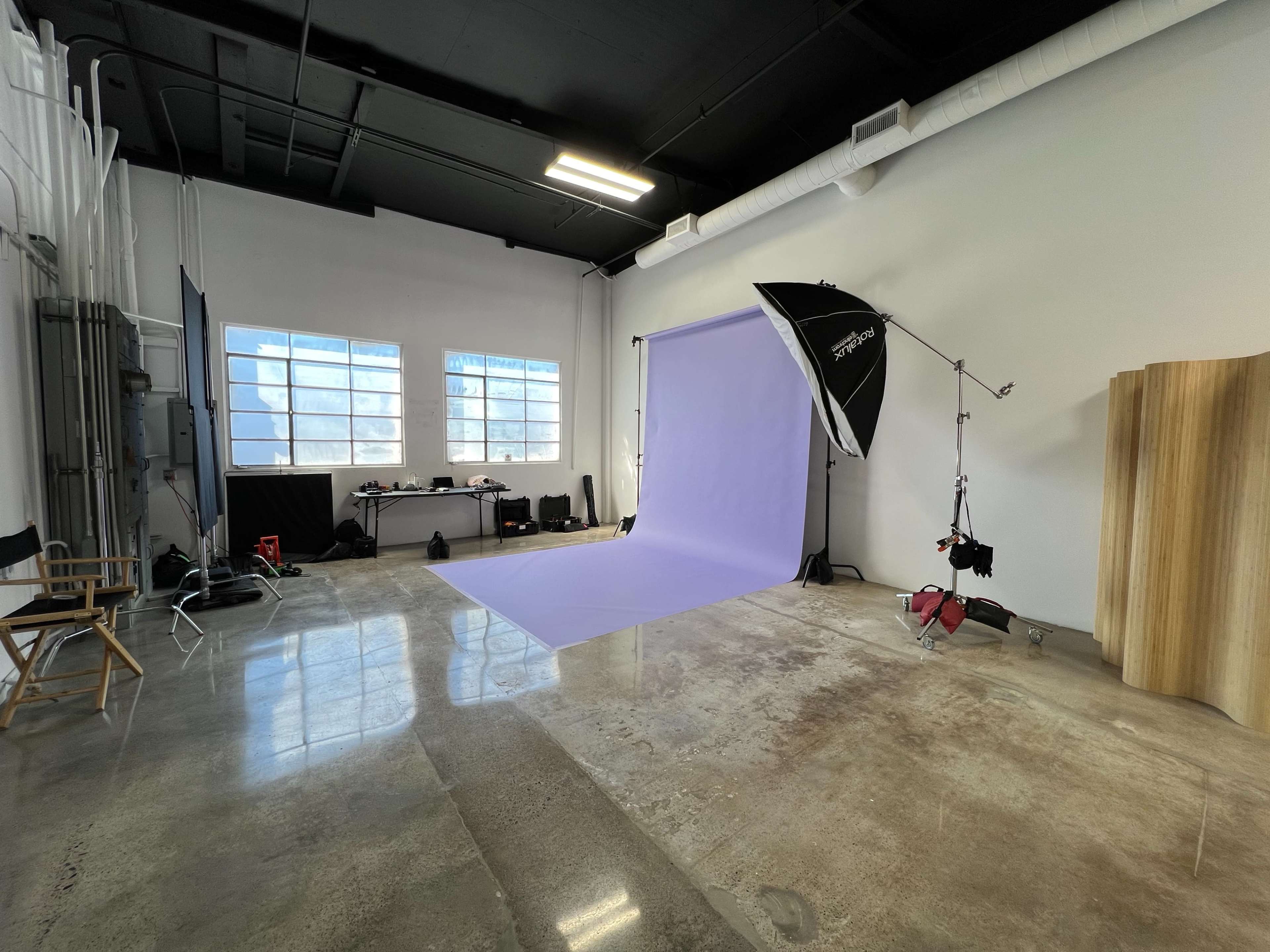 A photography studio with a purple backdrop, professional lighting equipment, and minimalist furnishings.