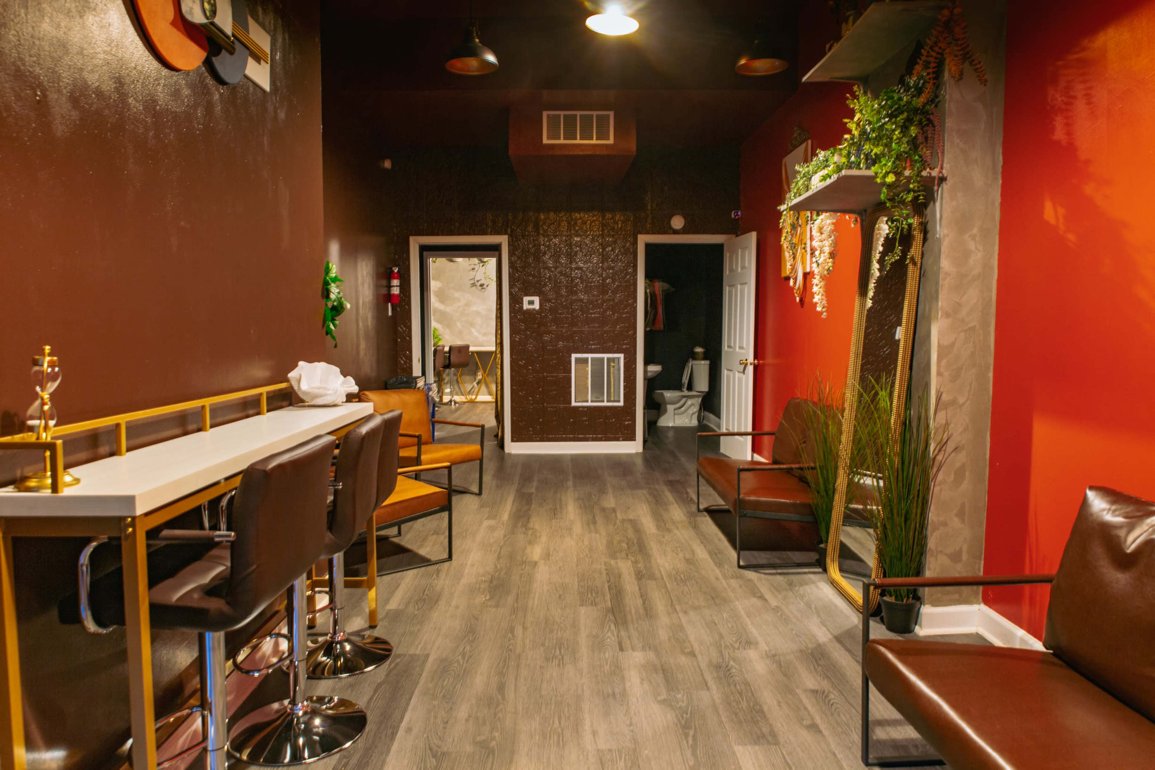 A narrow corridor with a bar-style seating area on one side, wooden flooring, and a bathroom door at the far end.