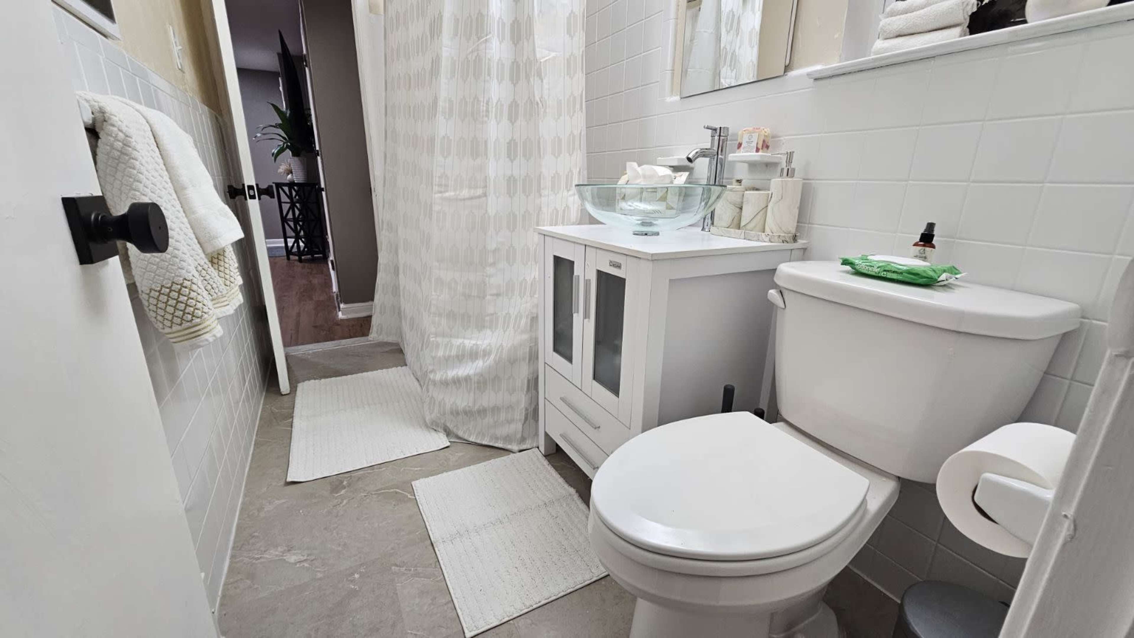 A small bathroom featuring a toilet, a white sink with a bowl design, and a shower area separated by a curtain.
