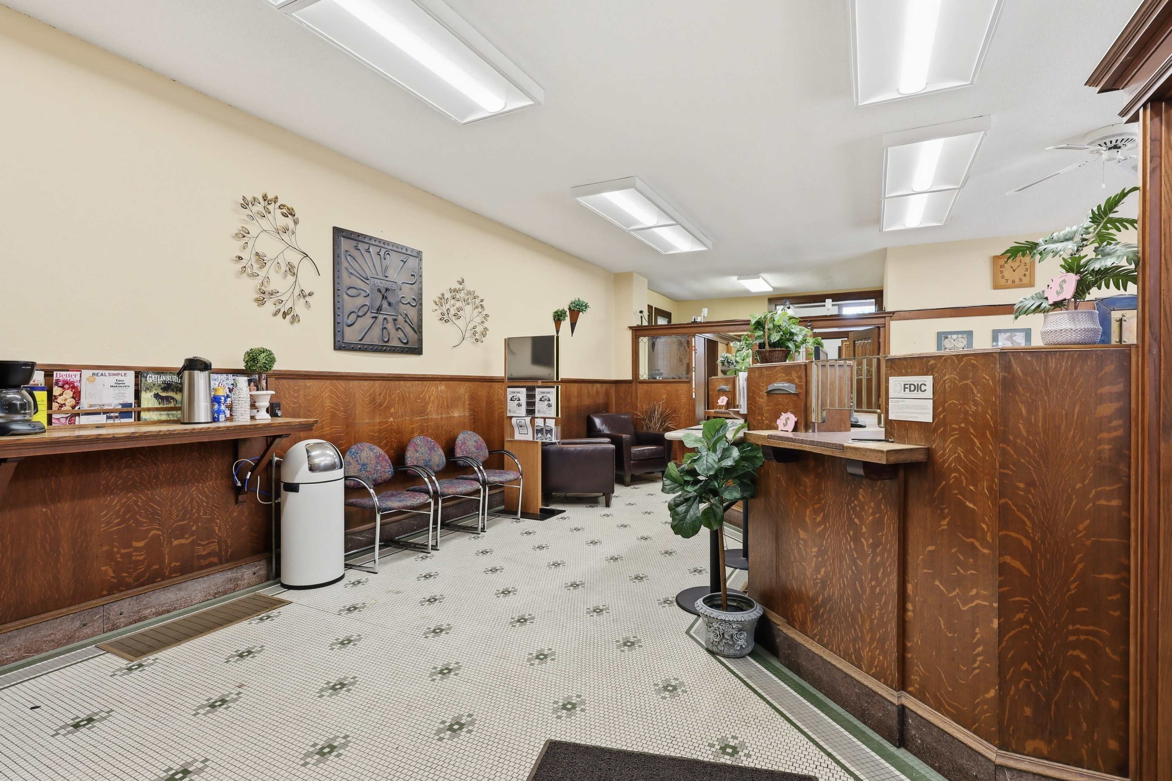 The image shows a reception area with wooden paneling, a front desk, seating, and various decorative wall elements.
