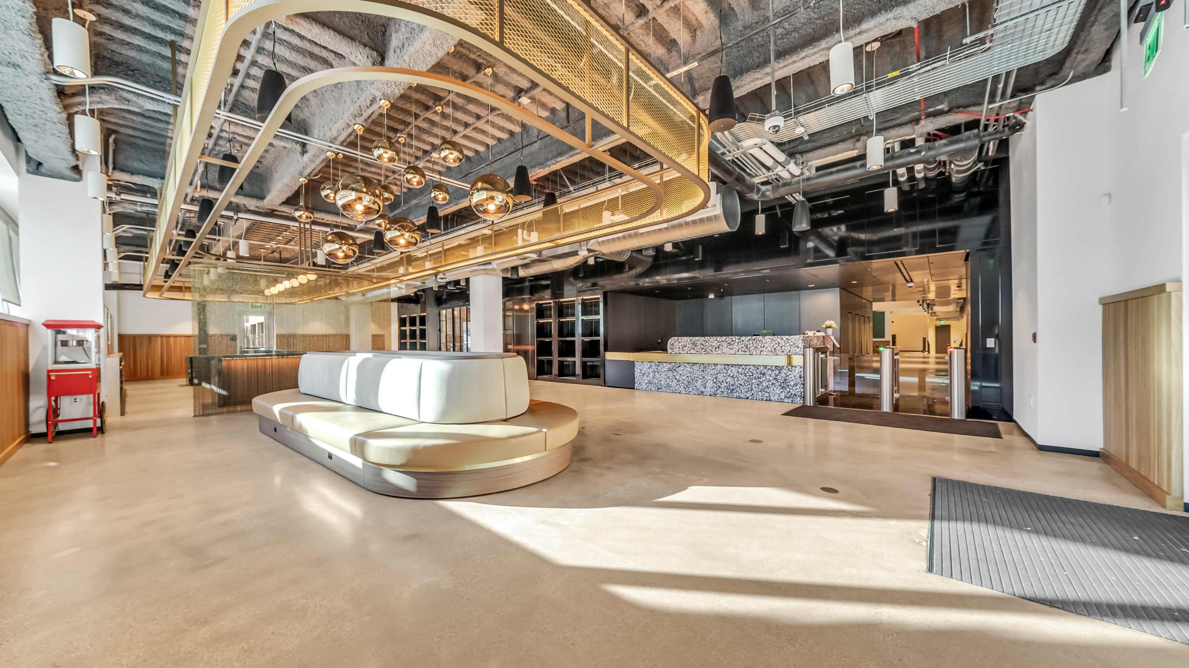 A modern lobby area featuring a curved seating arrangement, pendant lighting, and a reception desk.