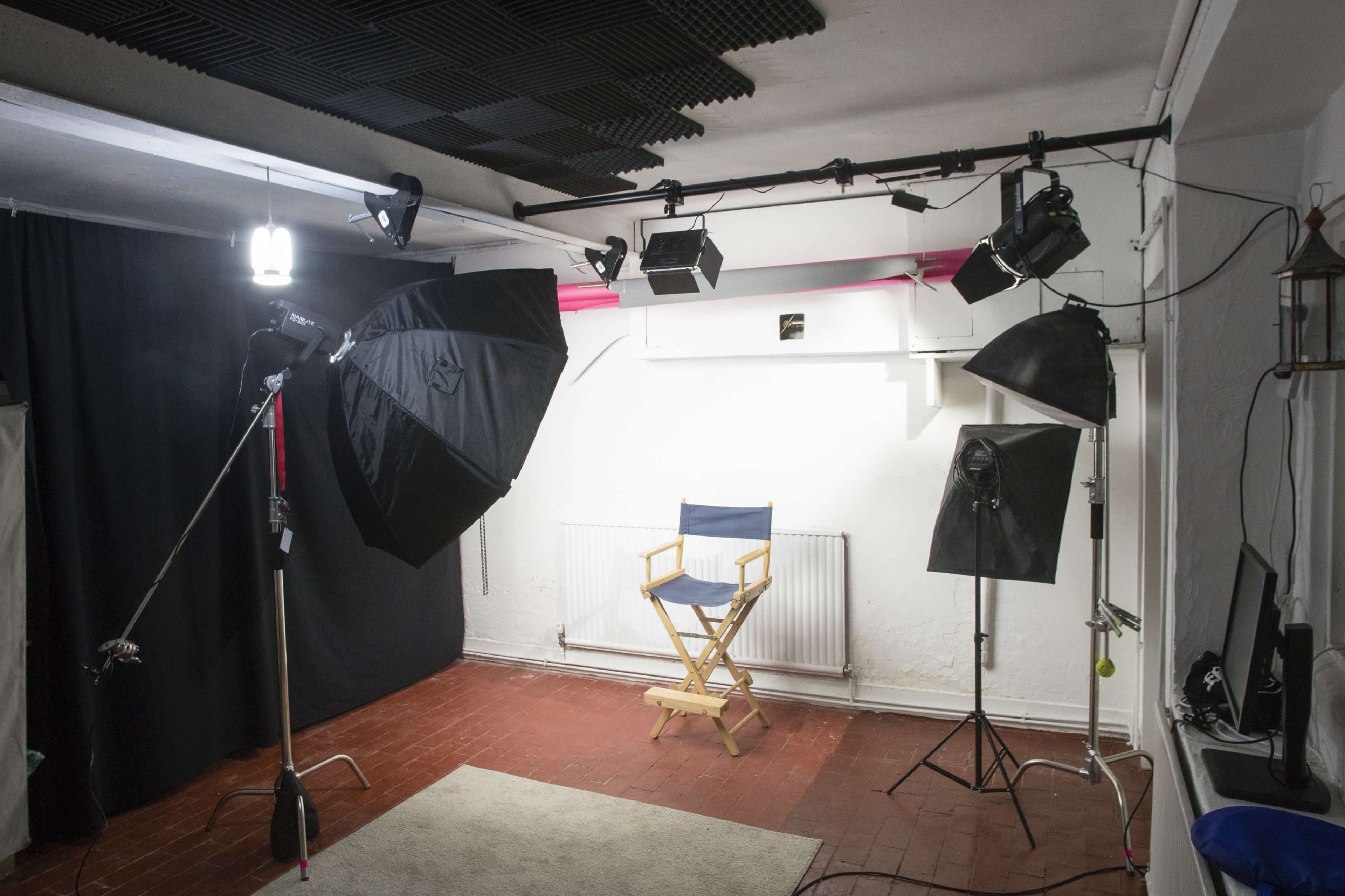 A photography studio is set up with various lighting equipment and a director's chair in the center.