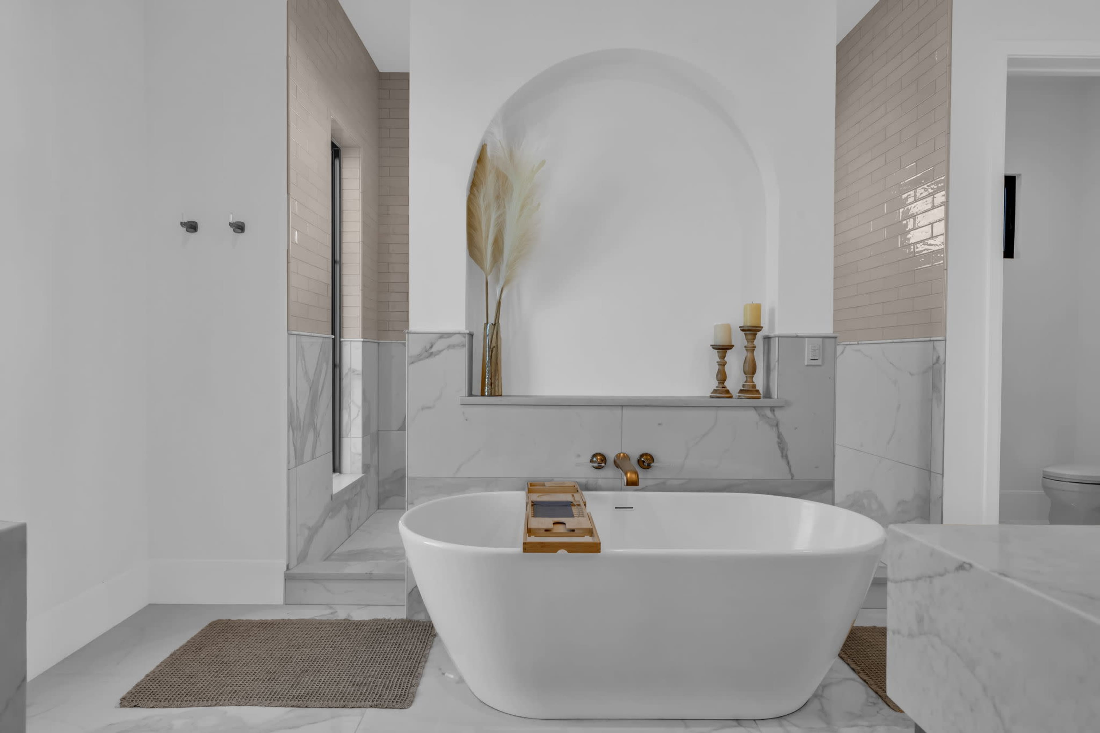 The image features a modern bathroom with a freestanding white bathtub, marble accents, and a decorative wall arch.