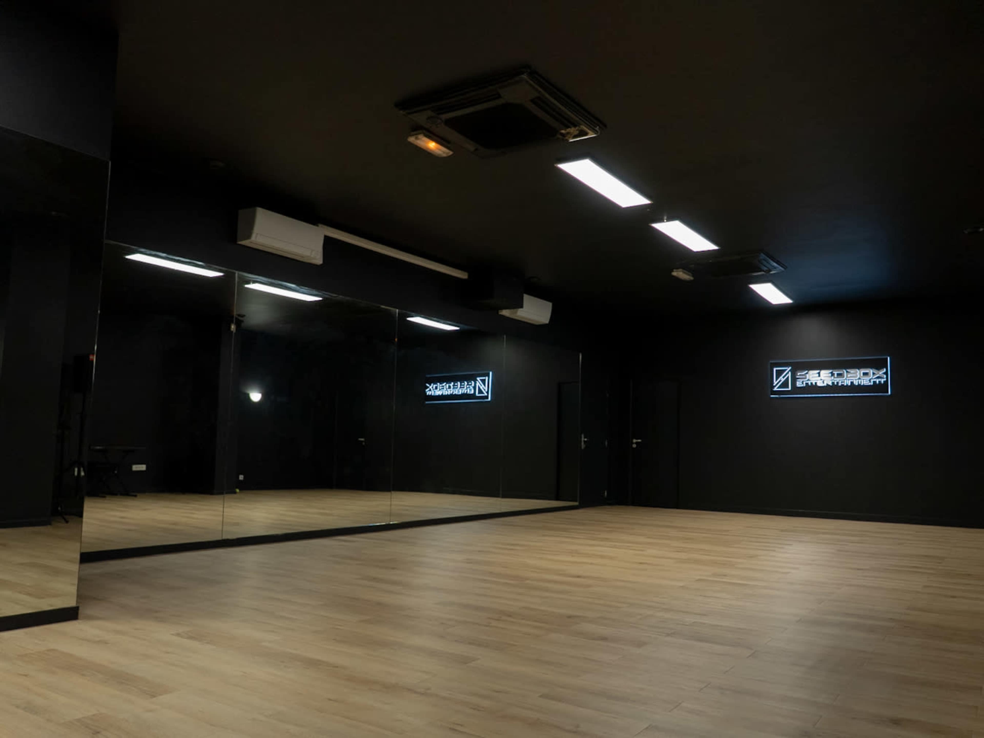 The image shows an empty dance studio with mirrored walls and minimal lighting.