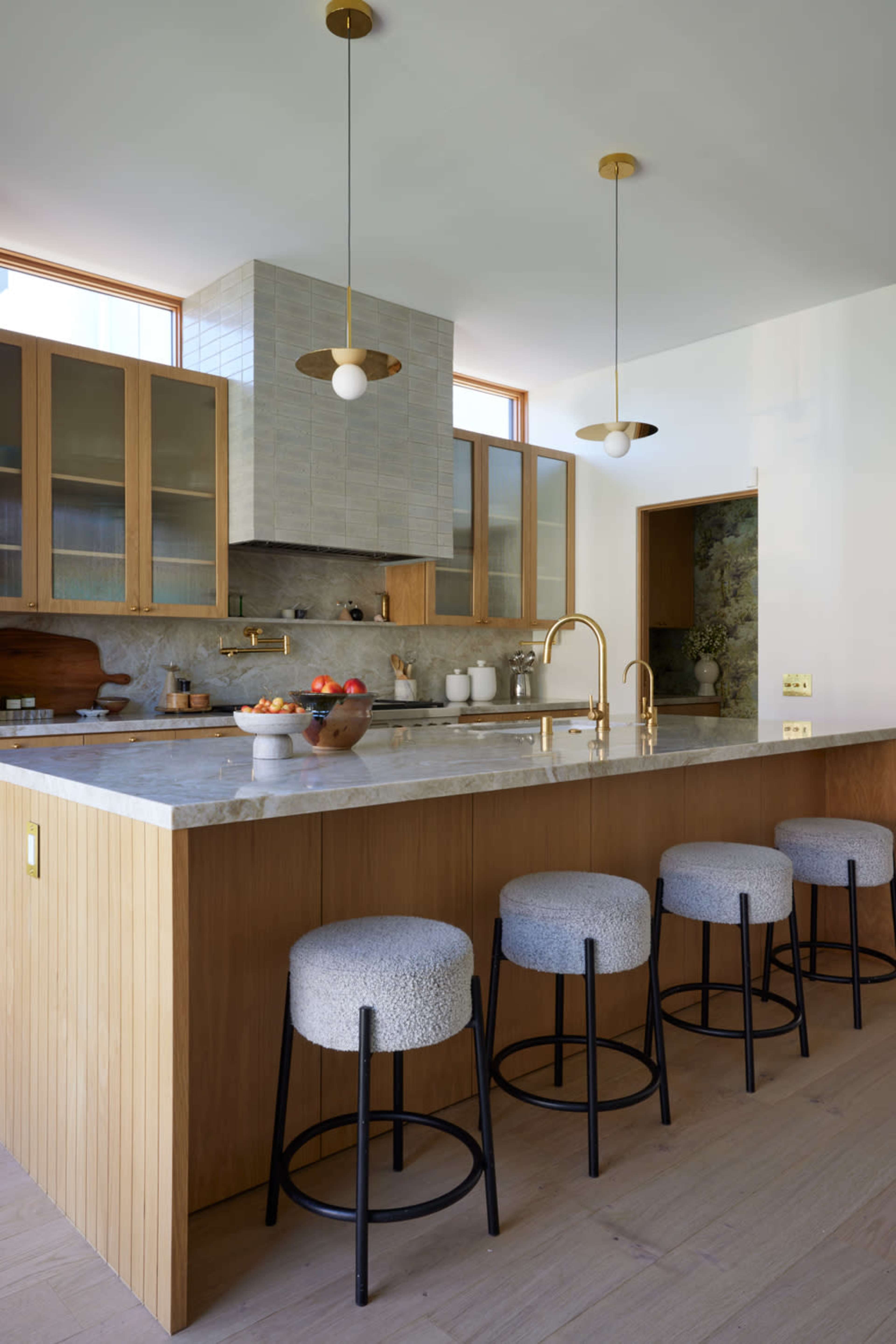 The kitchen features a large island with a marble countertop, wooden cabinetry, and modern pendant lights.