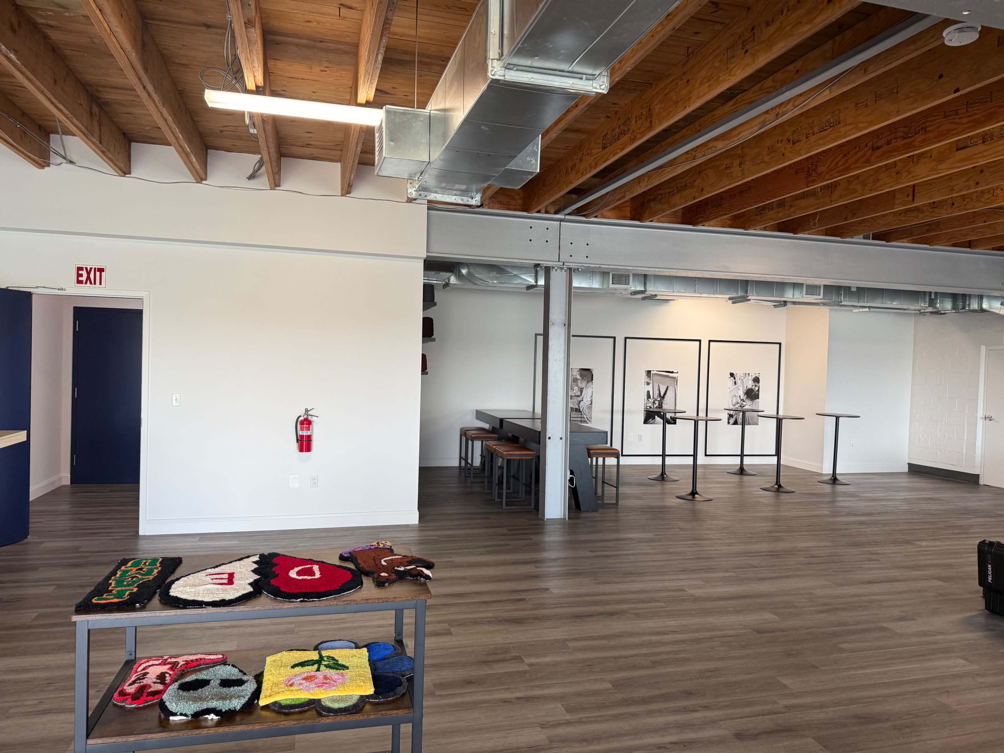 The image shows a spacious interior with wooden beams, a bar area on the left, and tables arranged for seating on the right.