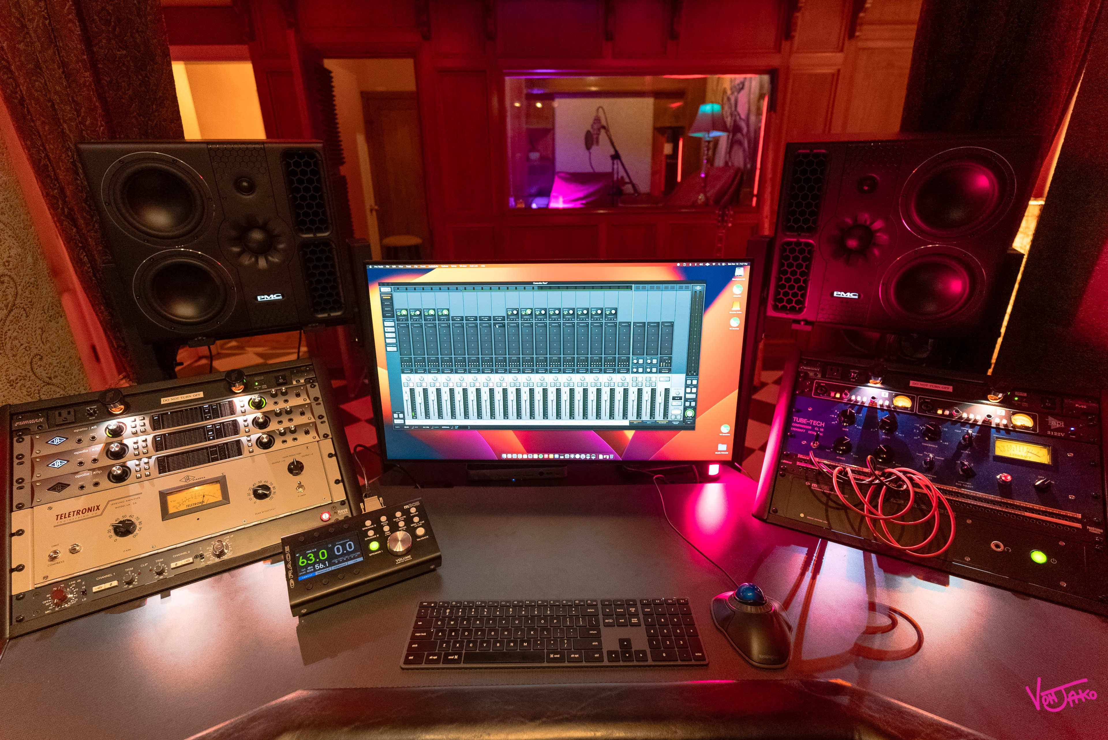 A music studio setup with audio equipment, a computer monitor displaying a digital audio workstation, and a keyboard on a desk.